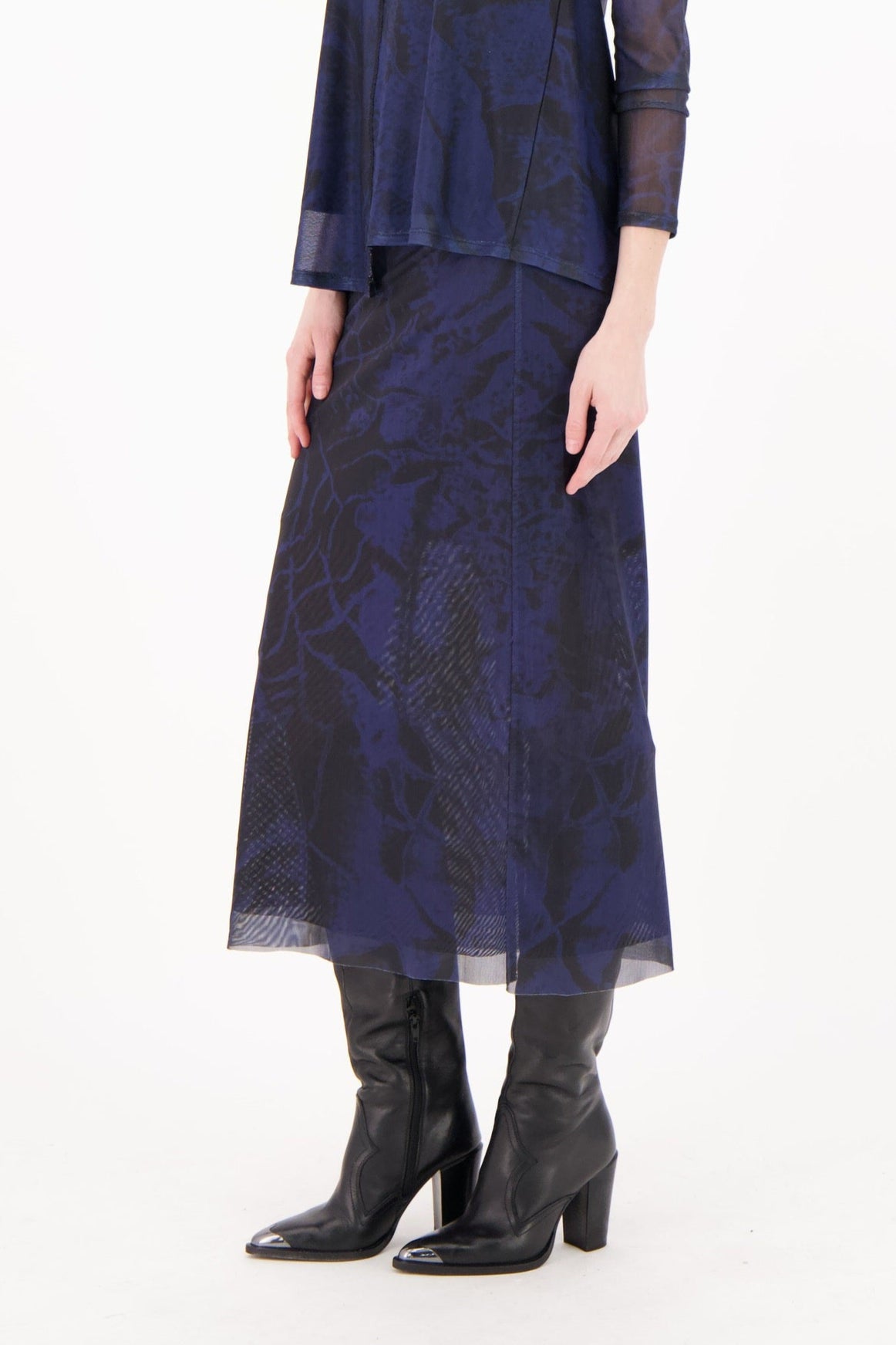 Woman wearing a navy blue dress with sheer sleeves on a white background