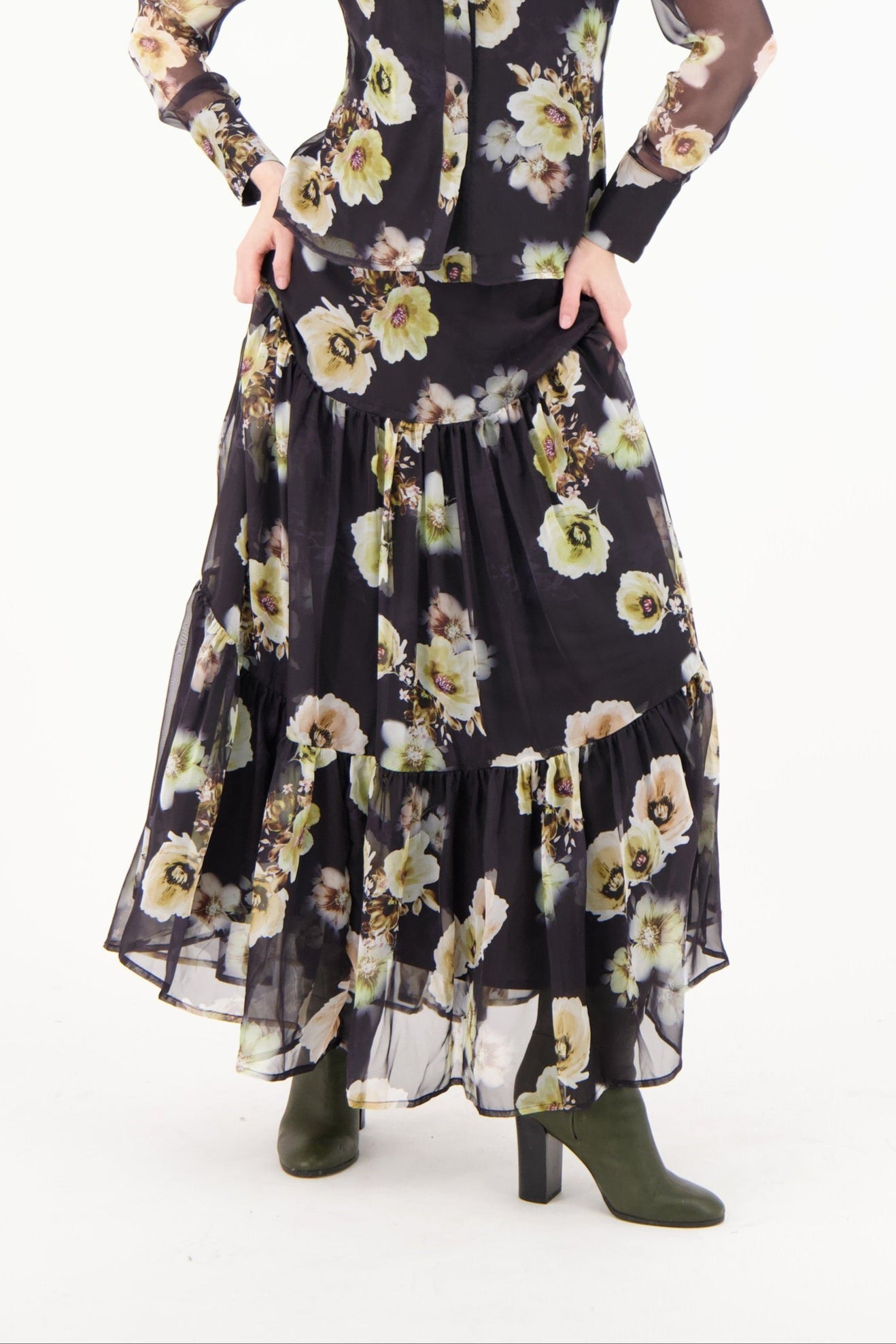 Person wearing a black floral dress with sheer sleeves on a white background
