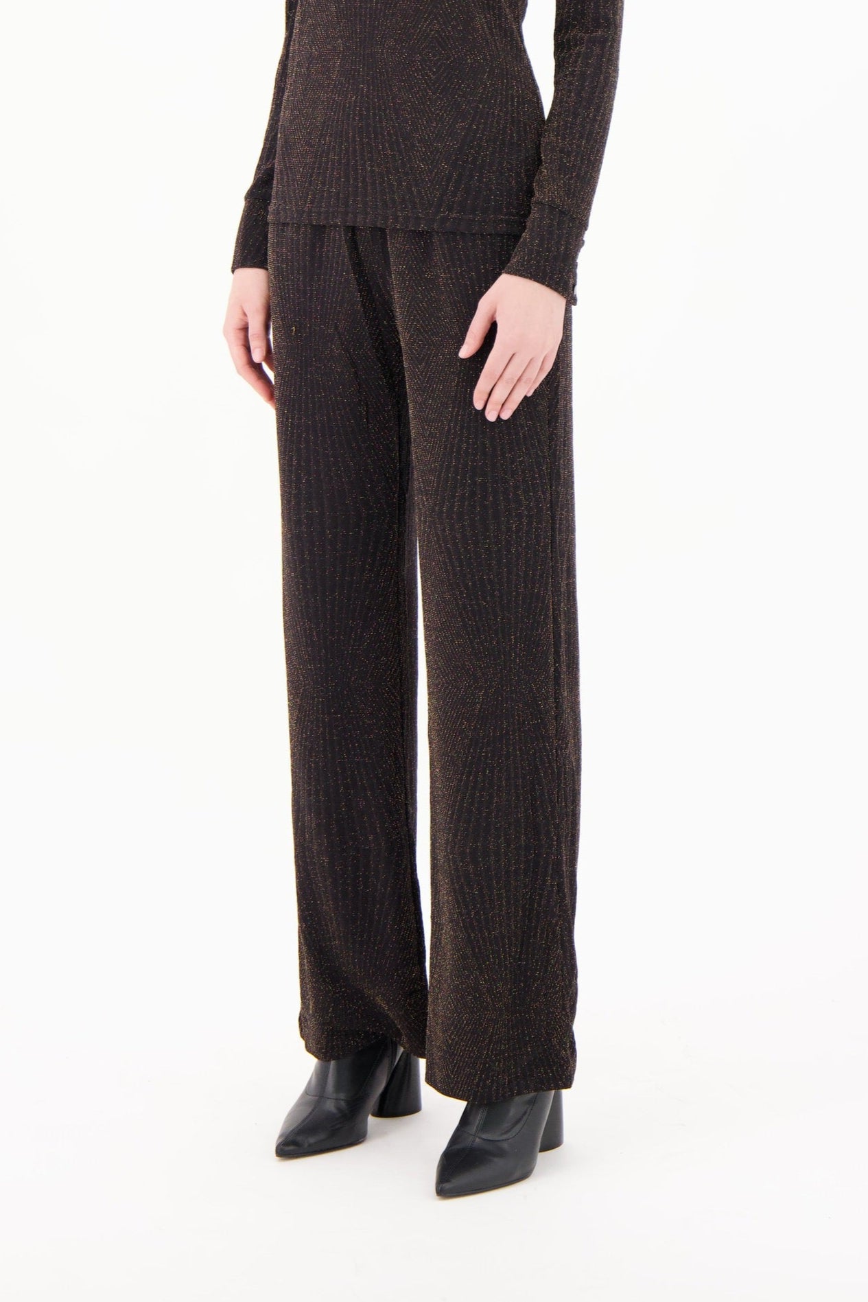 Person wearing brown ribbed knit pants and sweater on a white background