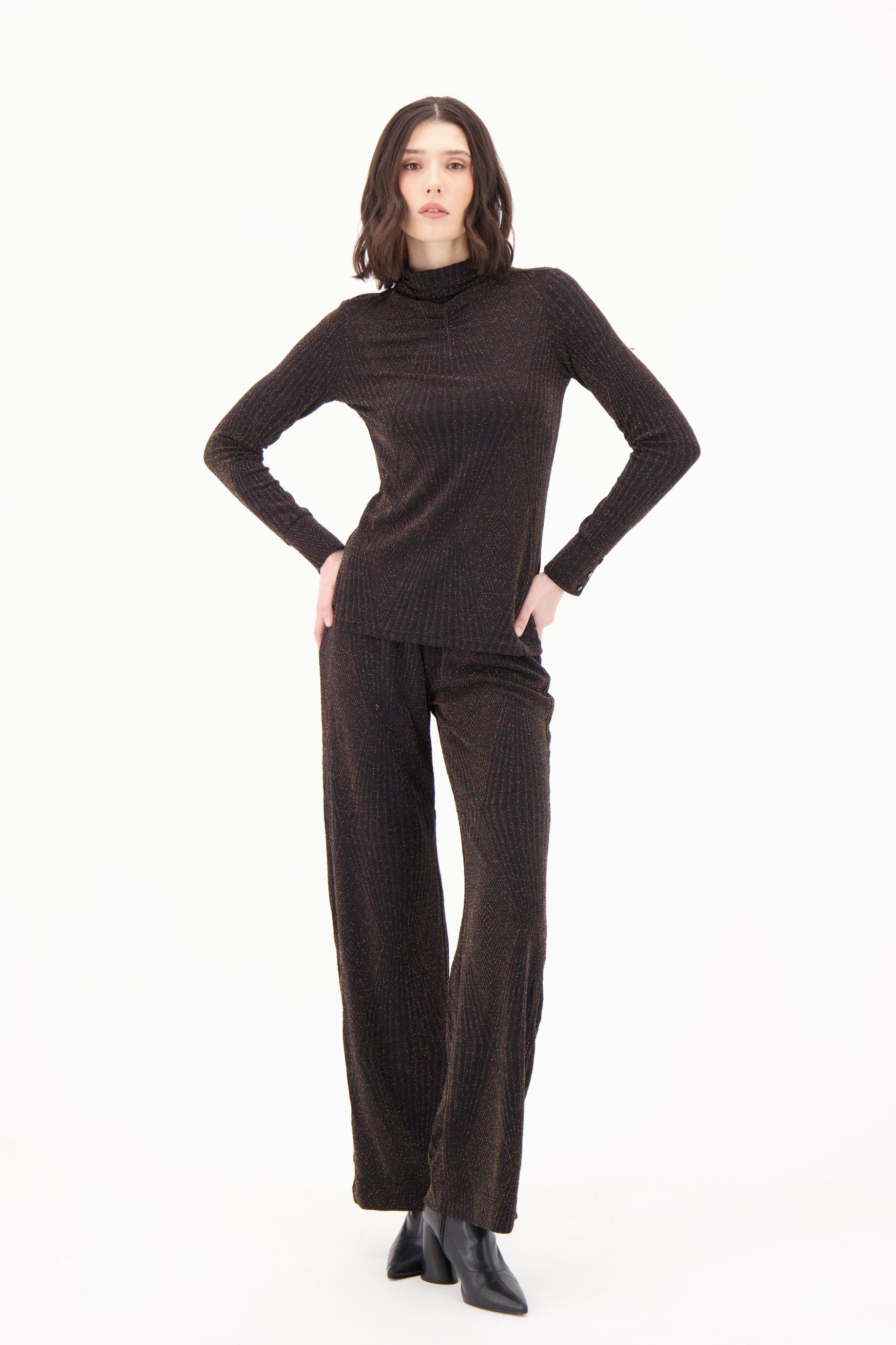 Woman wearing a brown ribbed turtleneck and pants on a white background