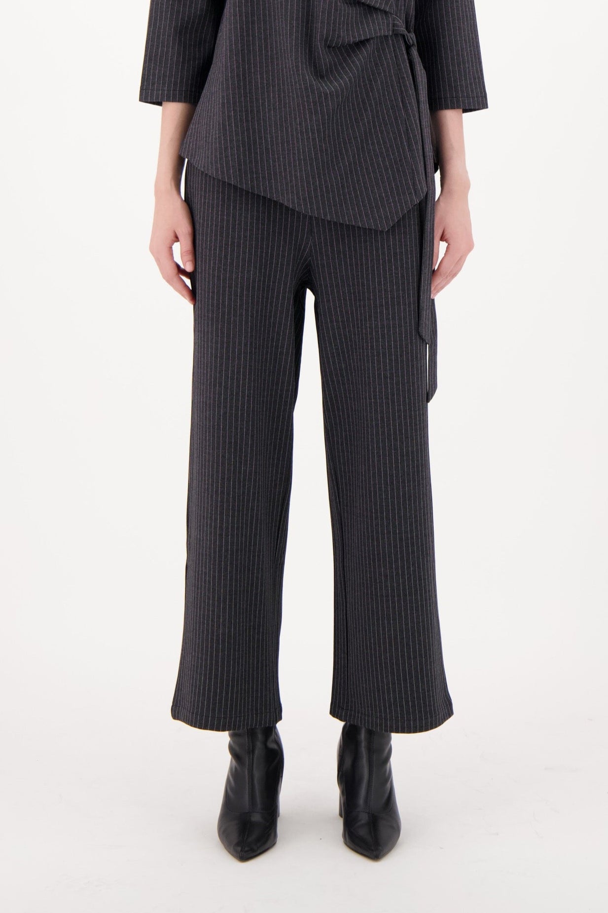 Woman wearing a dark gray outfit with wide-leg pants on a white background