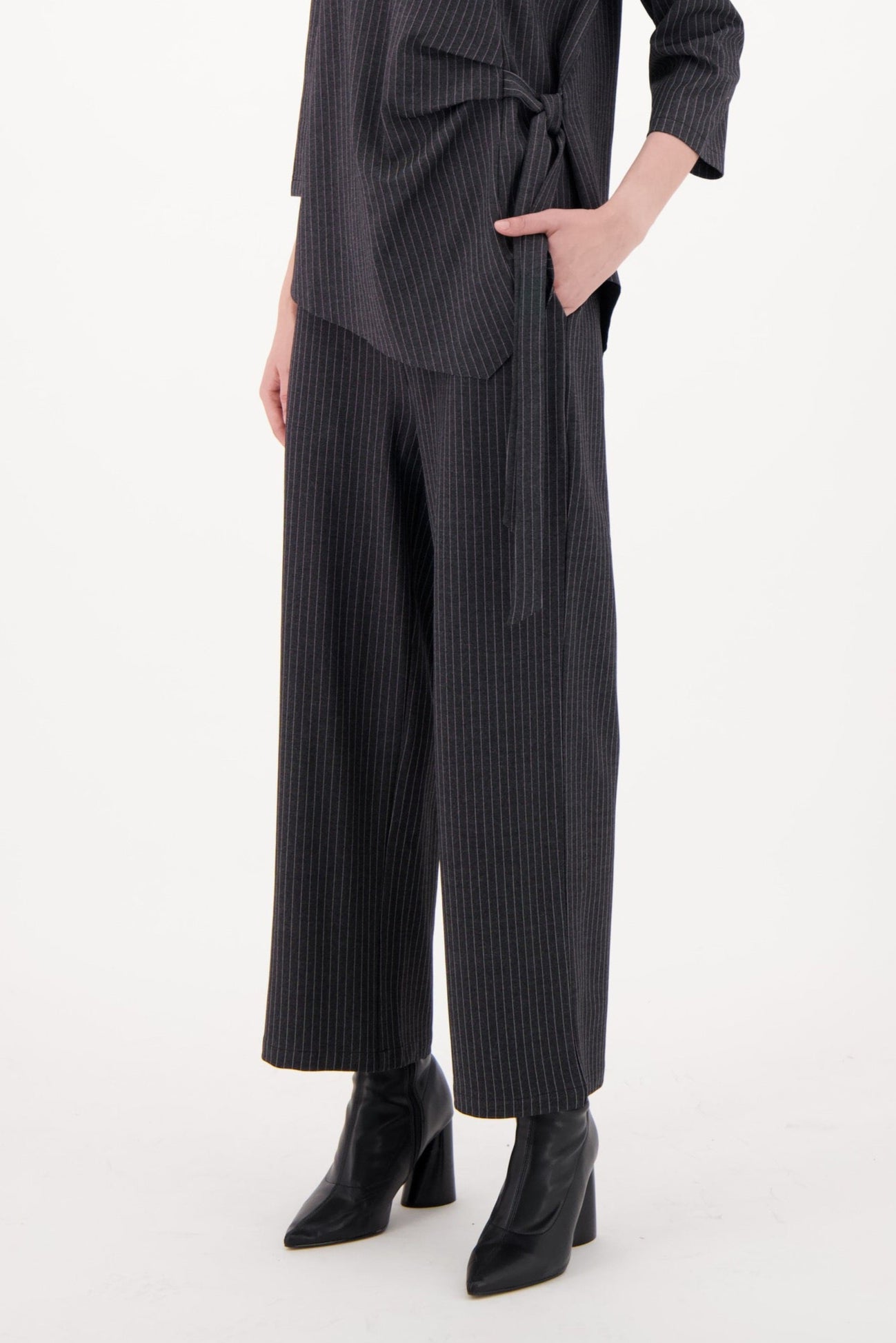 Woman wearing a dark gray long-sleeve top and wide-leg pants on a white background