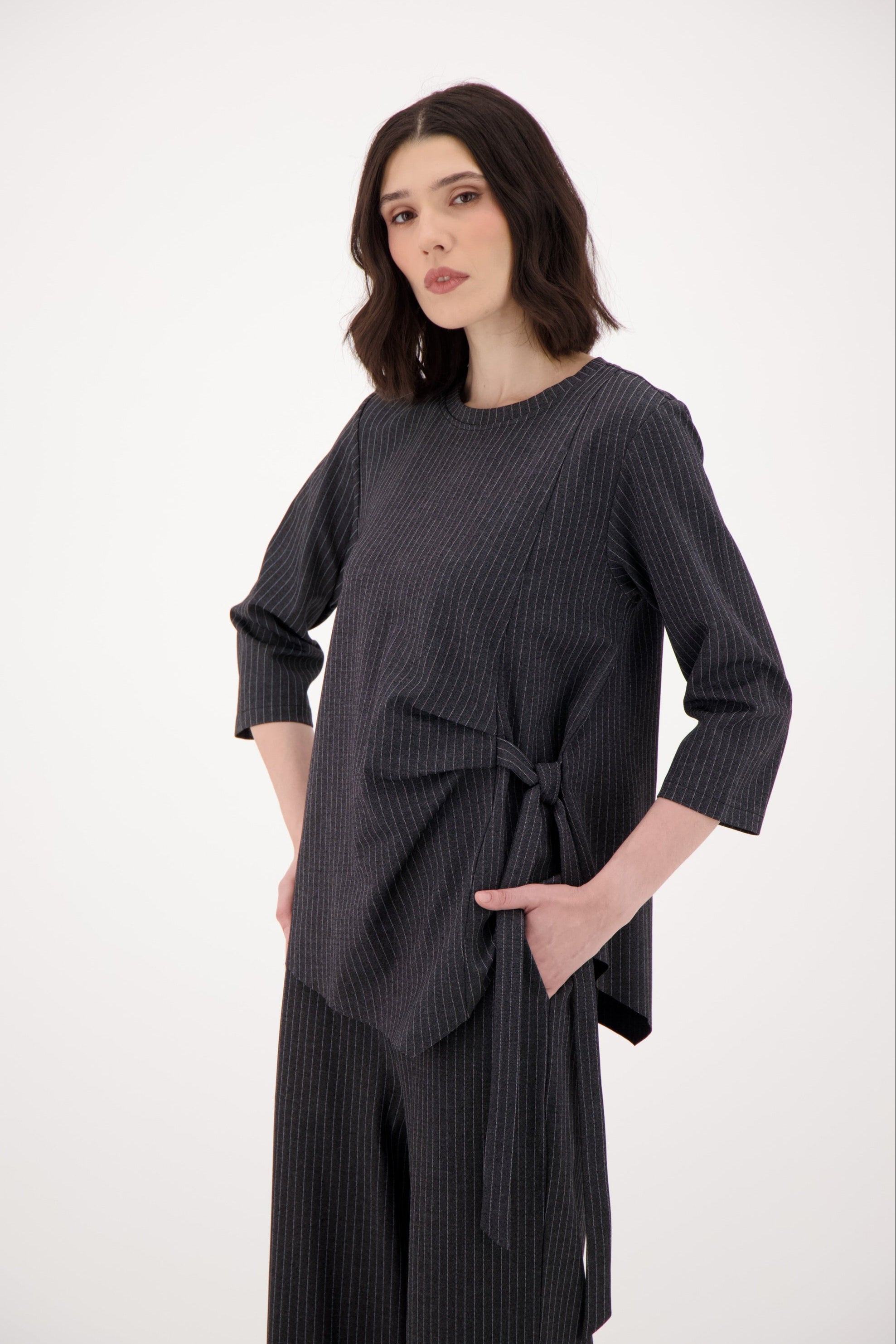 Woman wearing a black ribbed sweater and skirt set on a white background