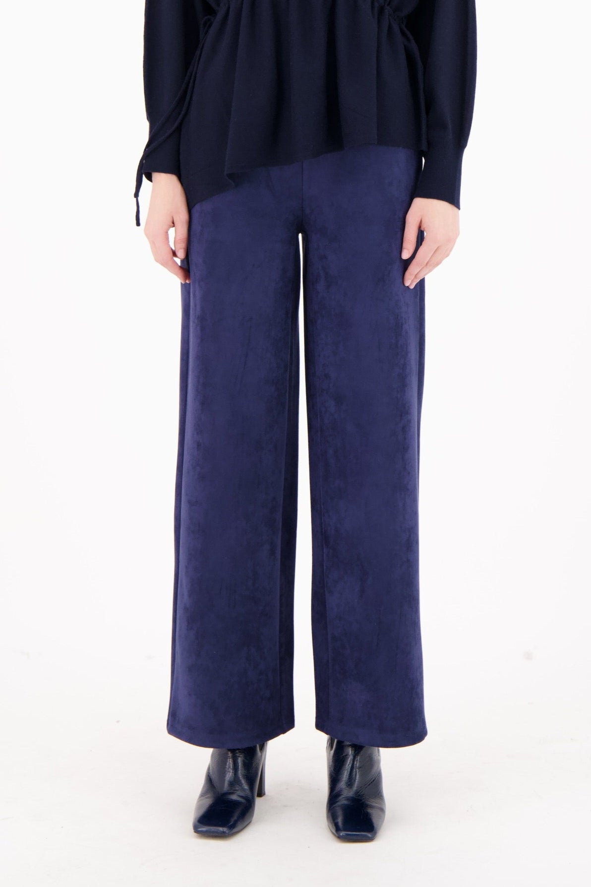 Woman wearing a navy blue top and wide-leg pants on a white background