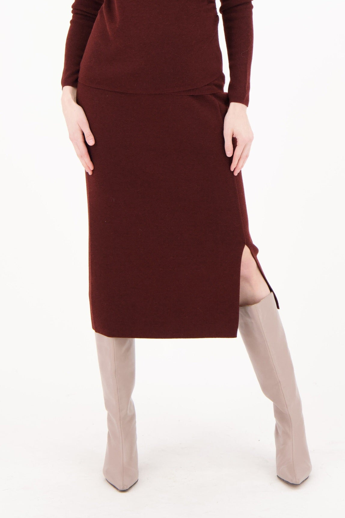 Woman wearing a burgundy dress with a slit on a white background