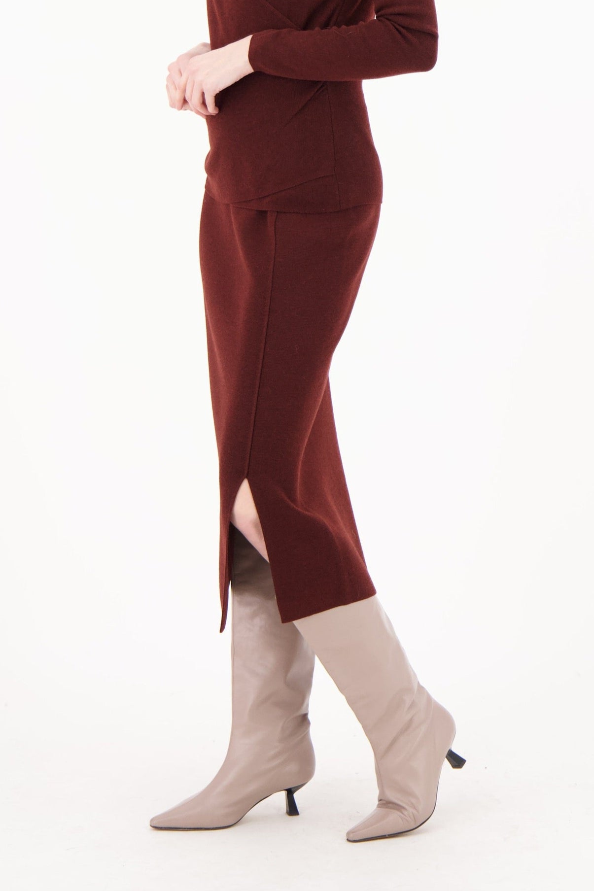 Woman wearing a burgundy jumpsuit with a slit on a white background