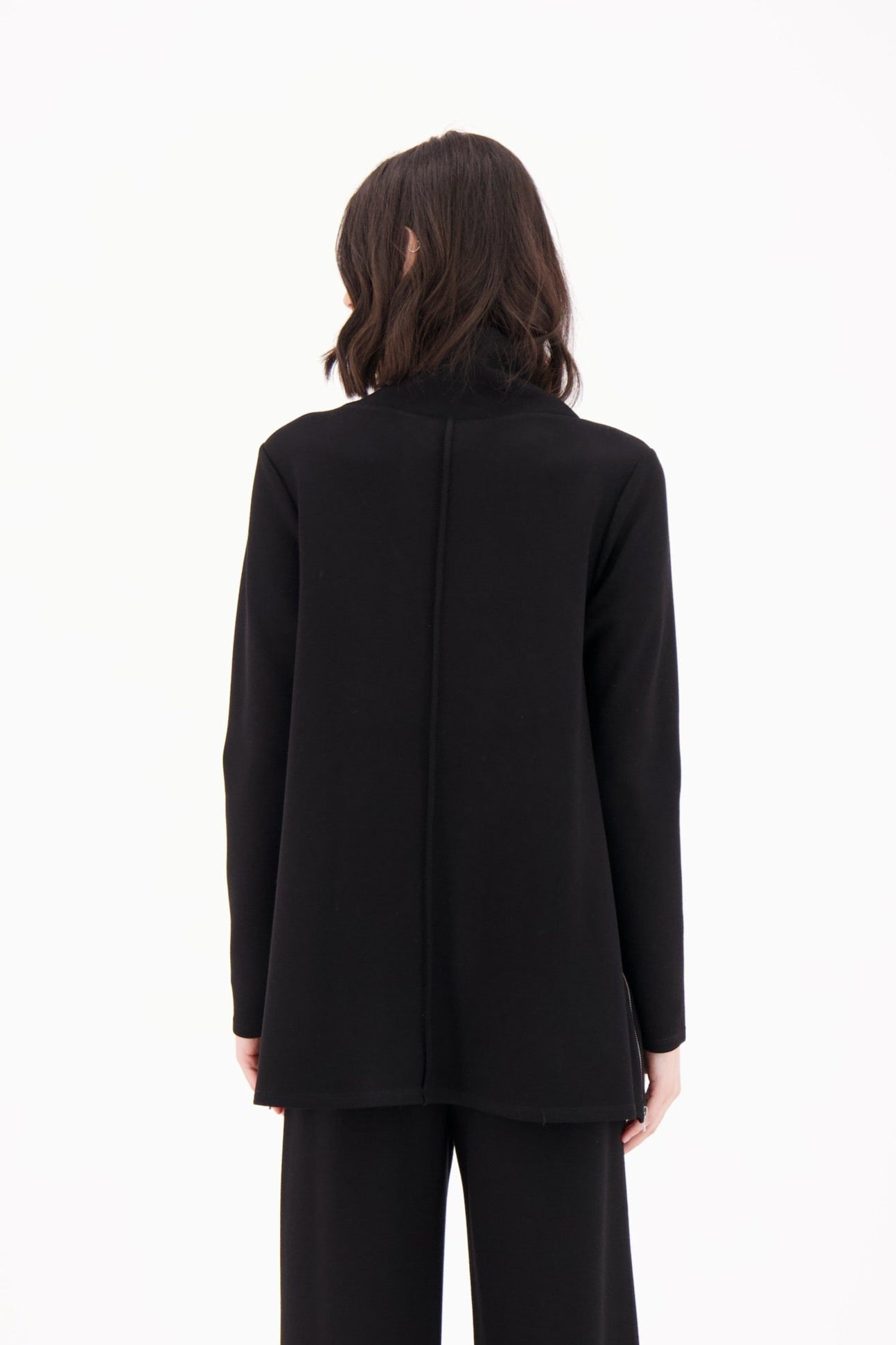 Person wearing a black suit standing against a white background