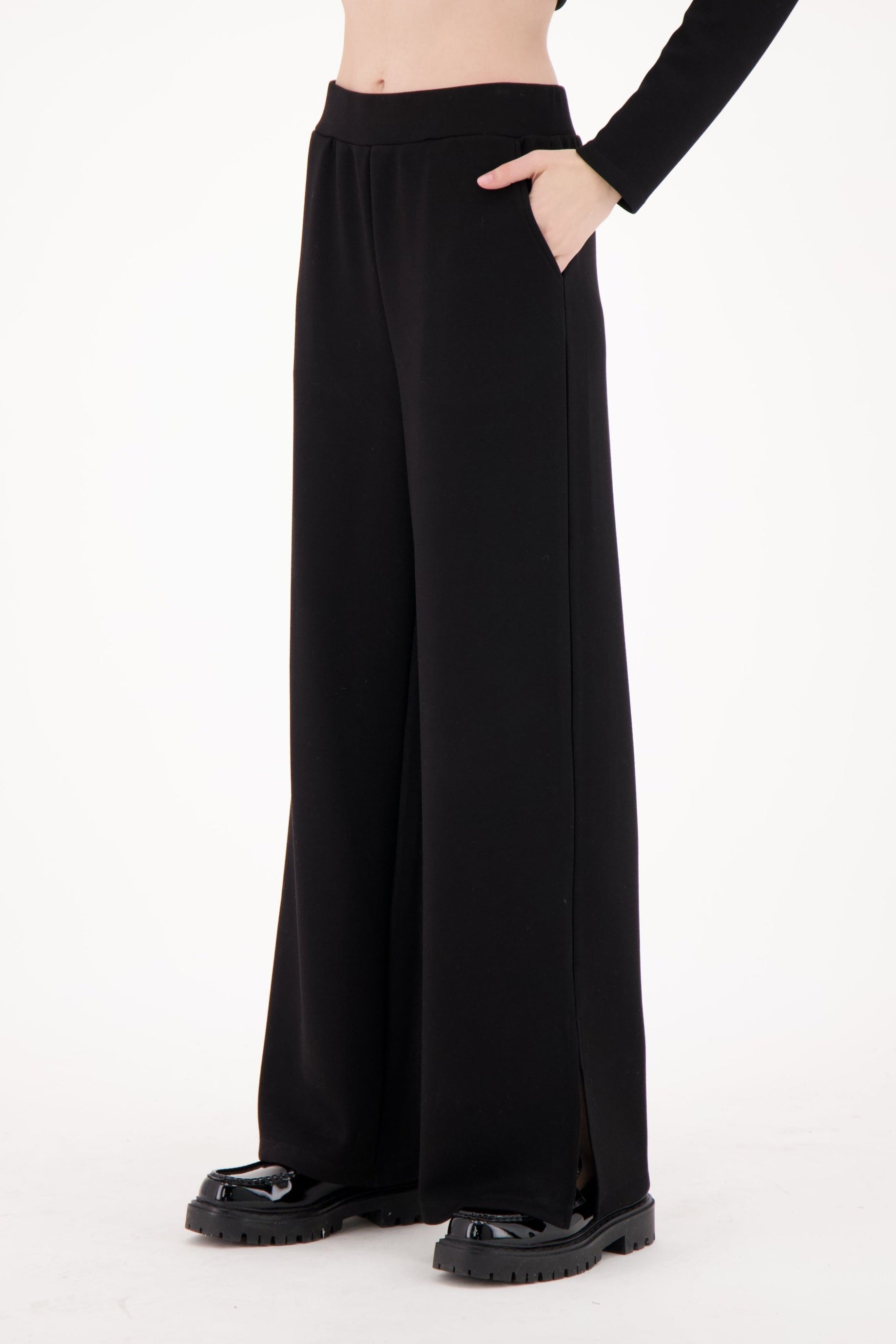 Black wide-leg pants worn by a person on a white background