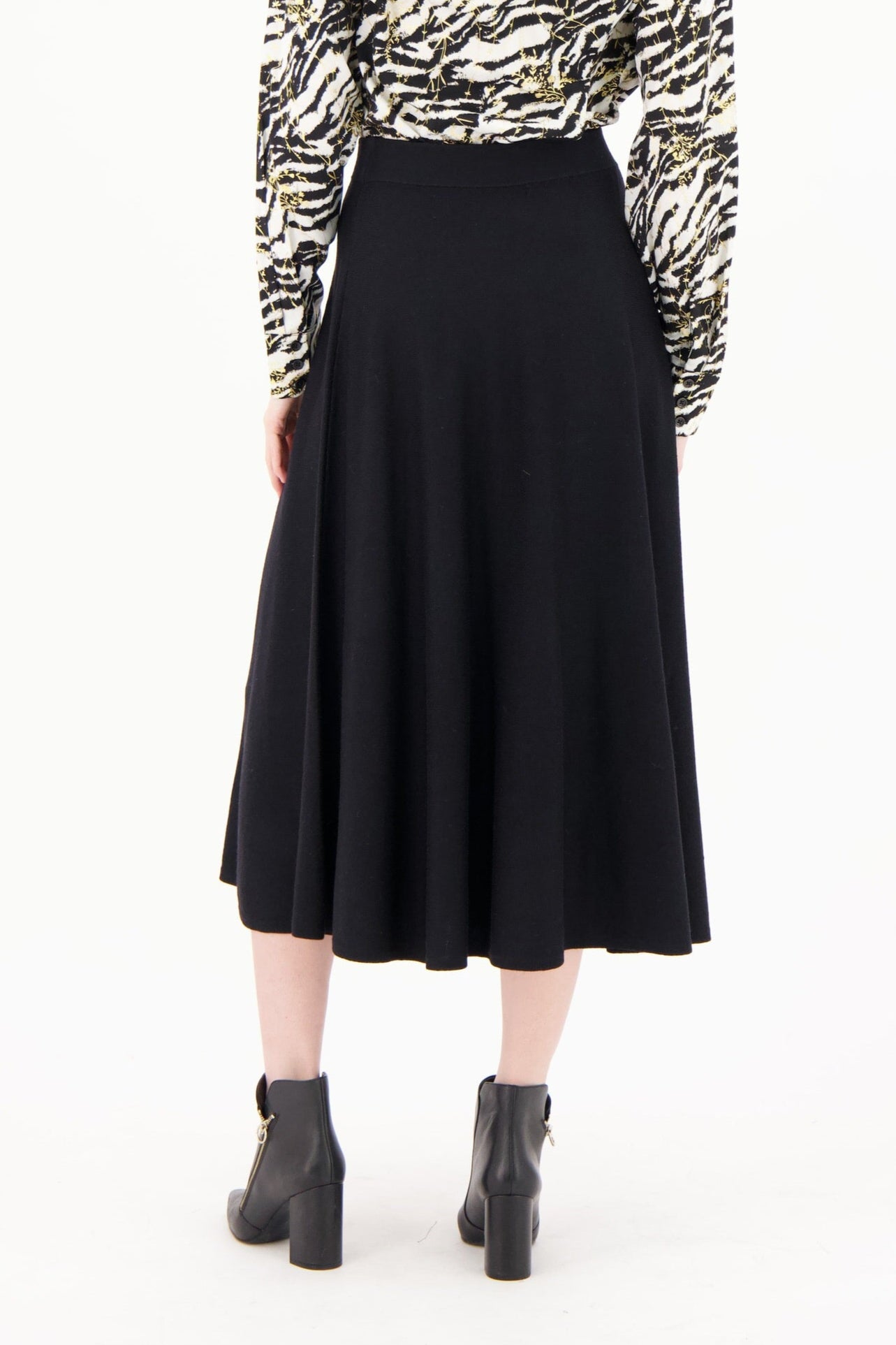 Woman wearing a zebra print shirt and black skirt on a white background