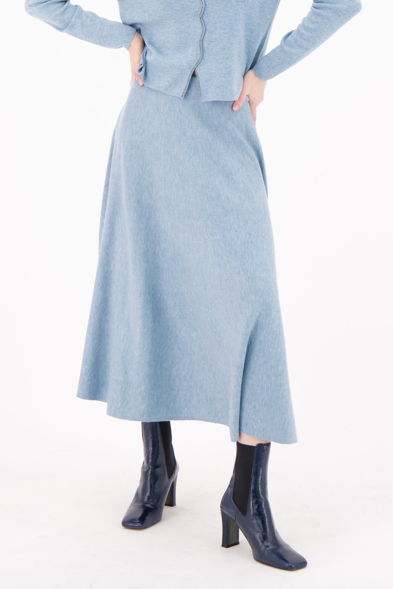 Woman wearing a light blue dress with a cardigan on a white background