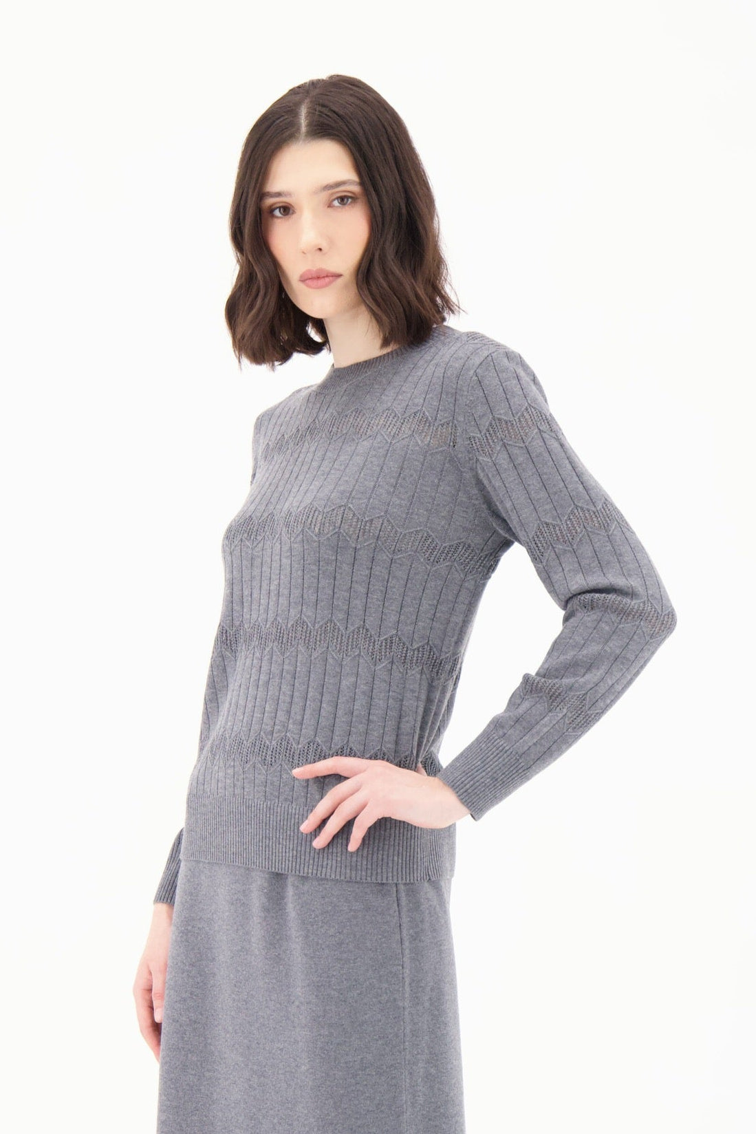 Woman wearing a gray ribbed dress with black knee-high boots on a white background