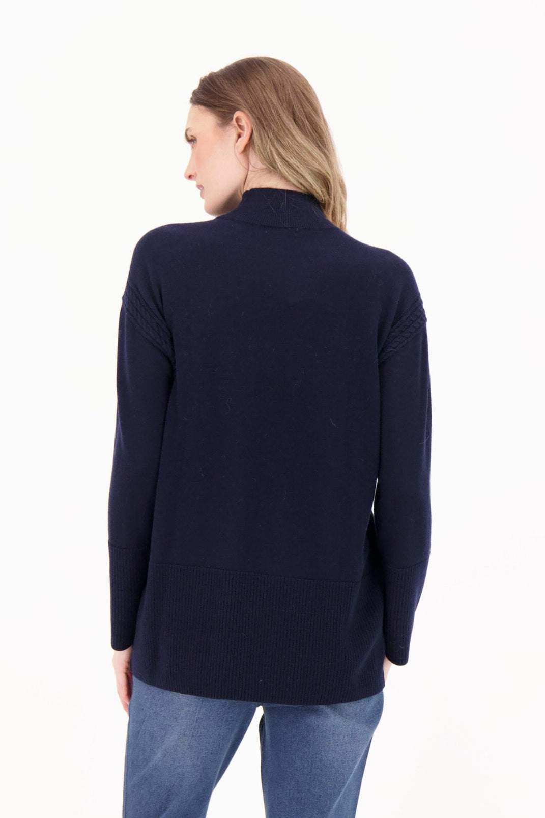 Woman wearing a navy blazer and blue jeans on a white background