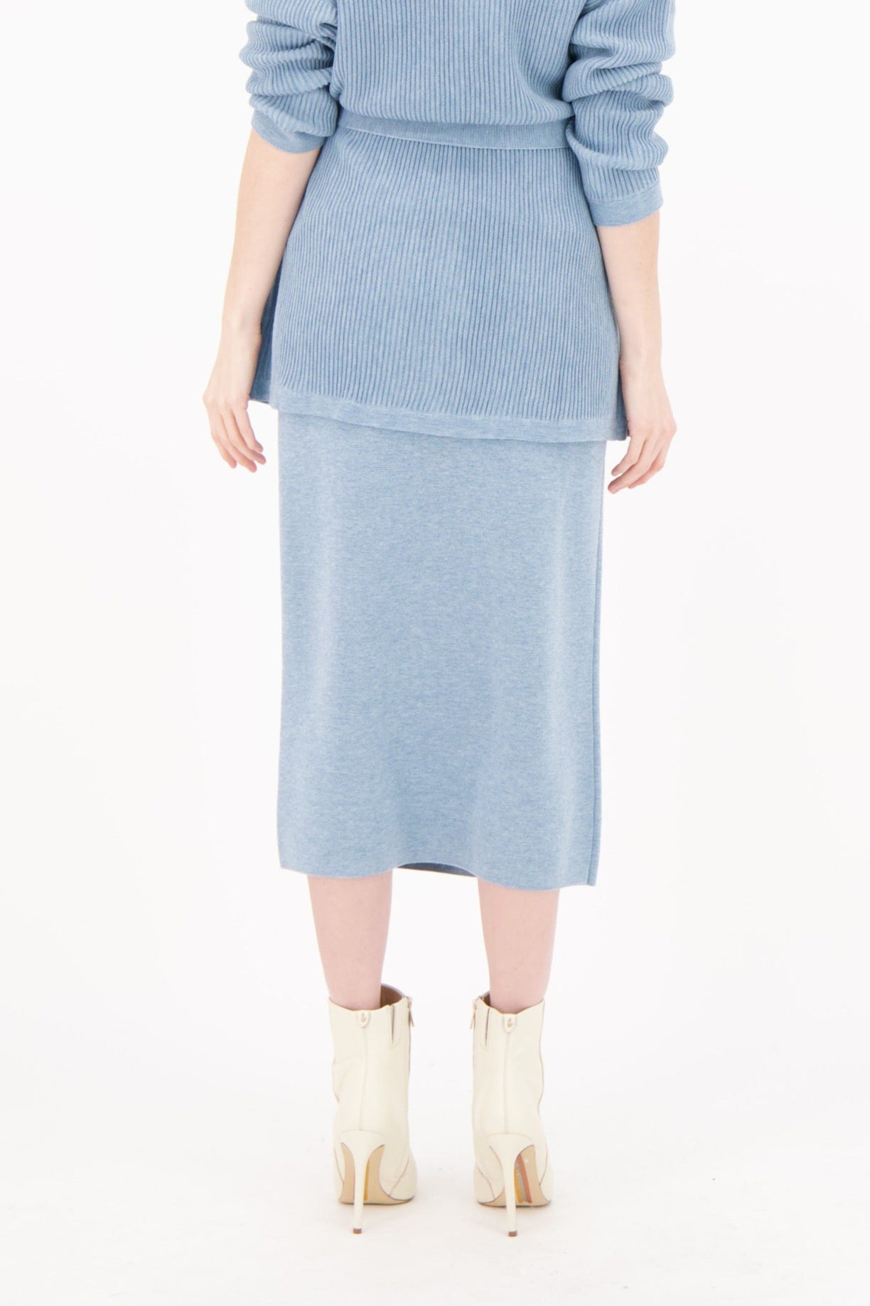 Woman wearing a light blue knit outfit on a white background