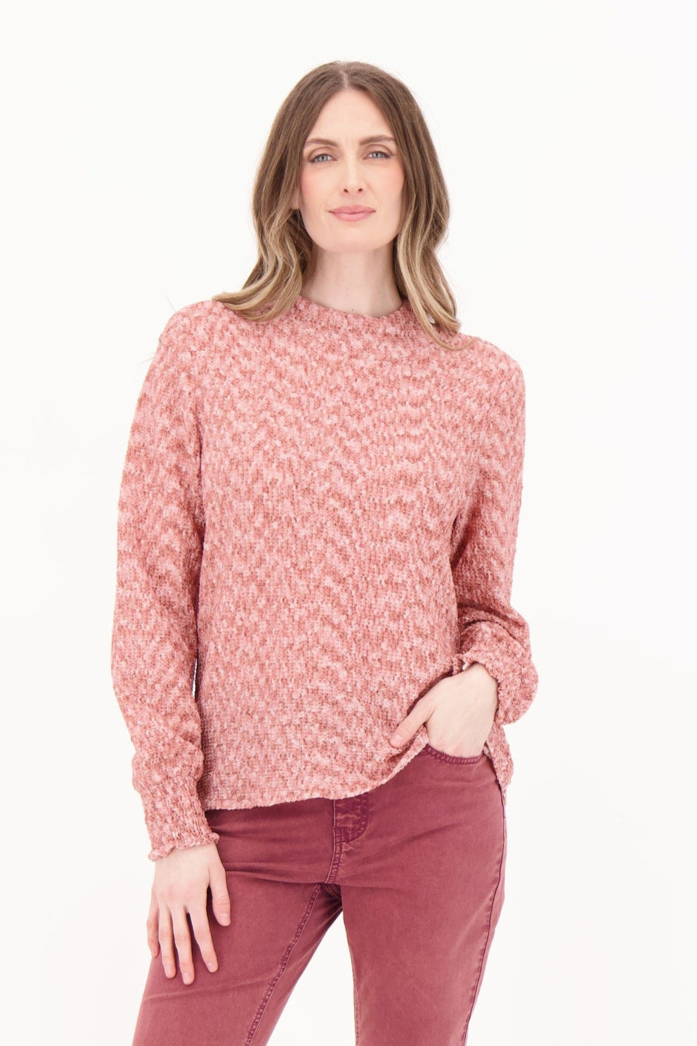 Woman wearing a pink patterned sweater and pink pants on a white background