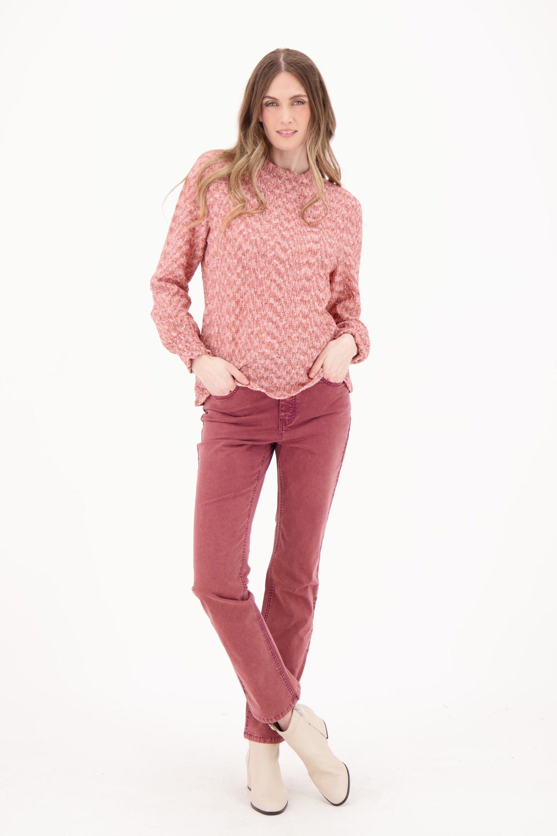 Woman wearing a pink patterned sweater and pink pants on a white background