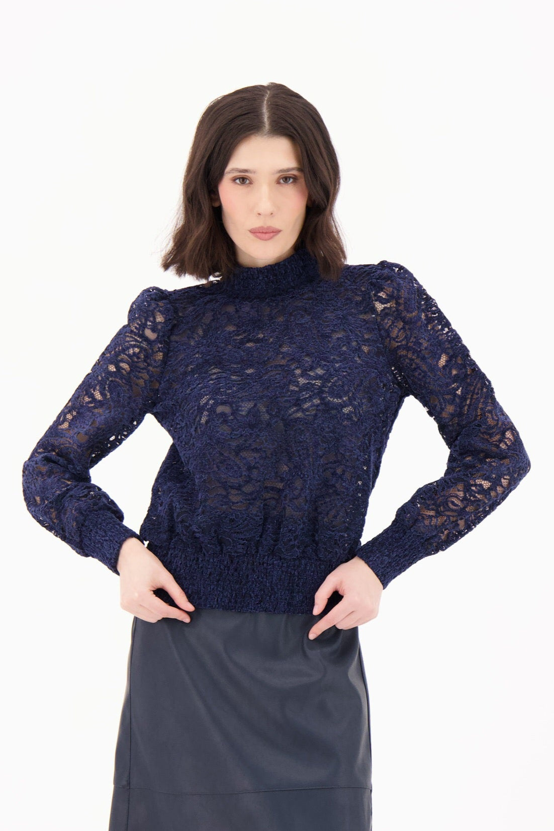 Woman wearing a navy lace top and black skirt on a white background