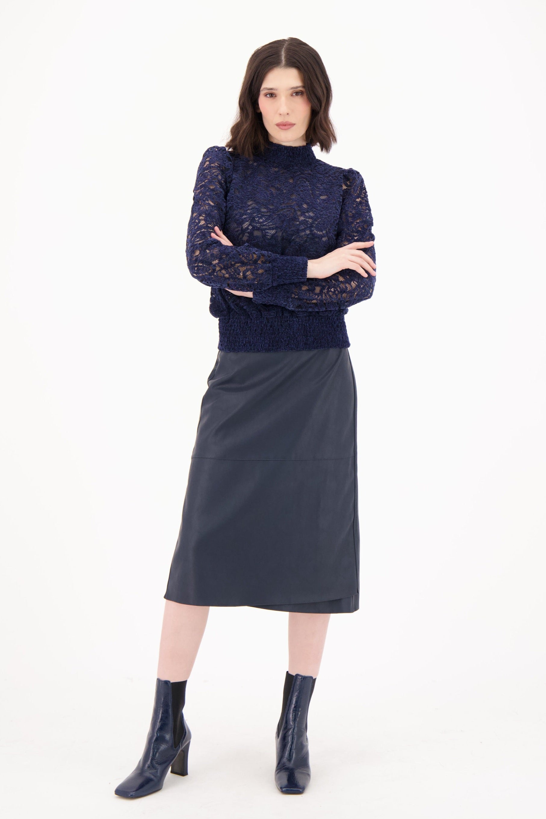 Woman wearing a navy patterned sweater and dark gray skirt on a white background