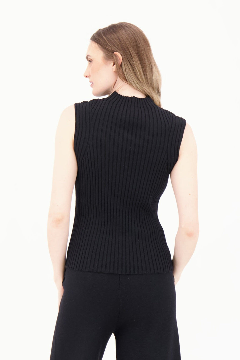 Woman wearing a black sleeveless top and black pants on a white background
