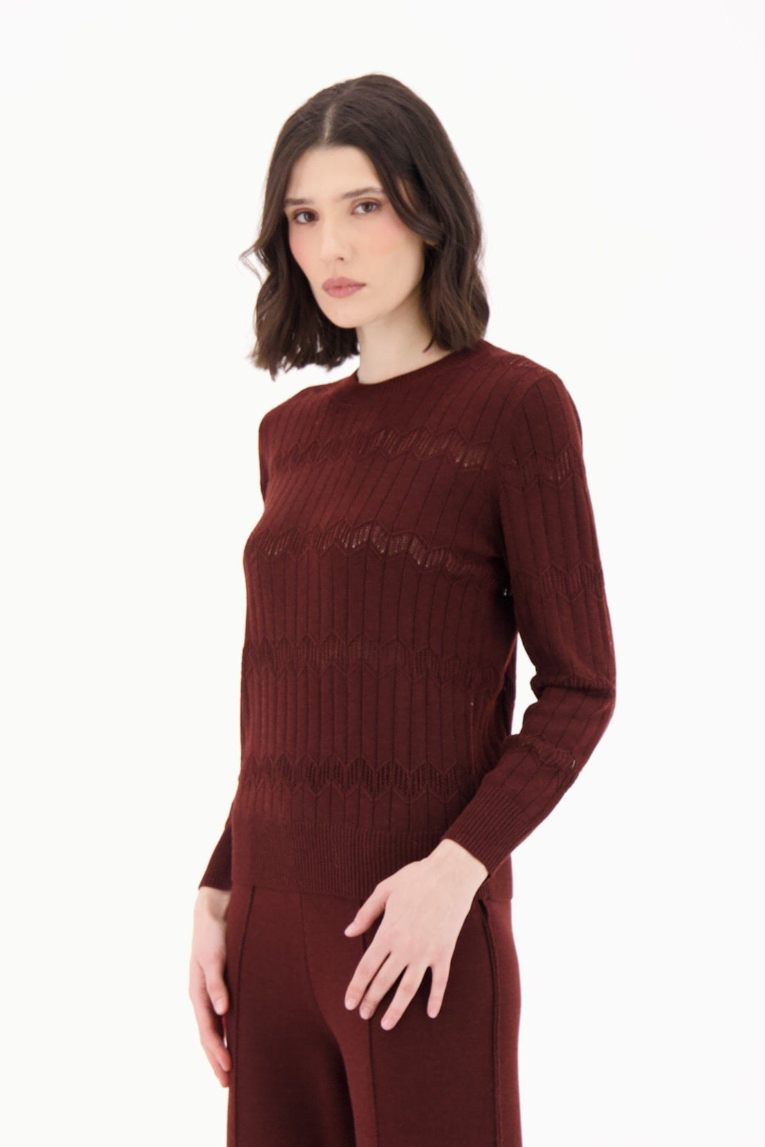 Woman wearing a burgundy knit jumpsuit on a white background