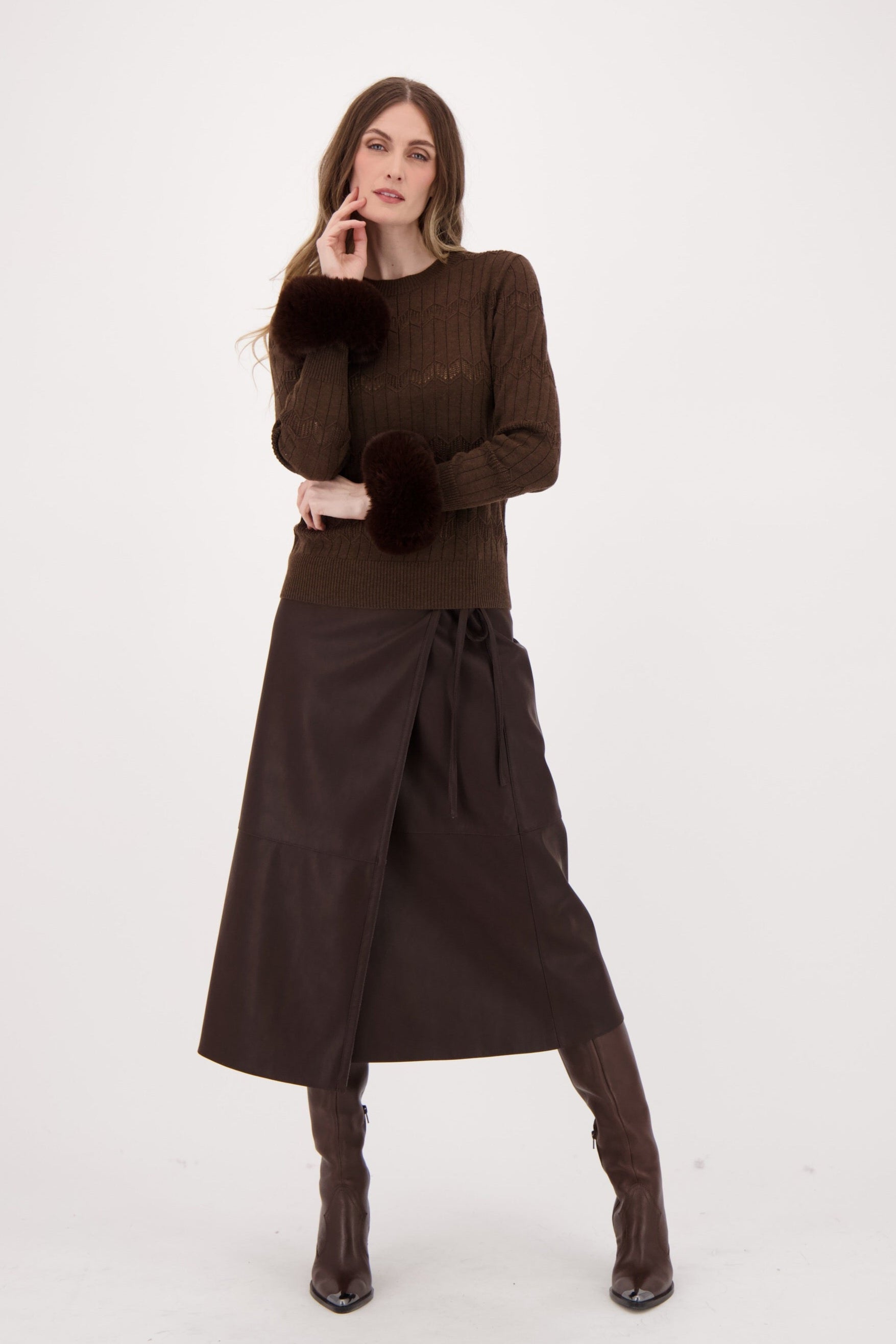 Woman wearing a brown outfit with a skirt and sweater on a white background