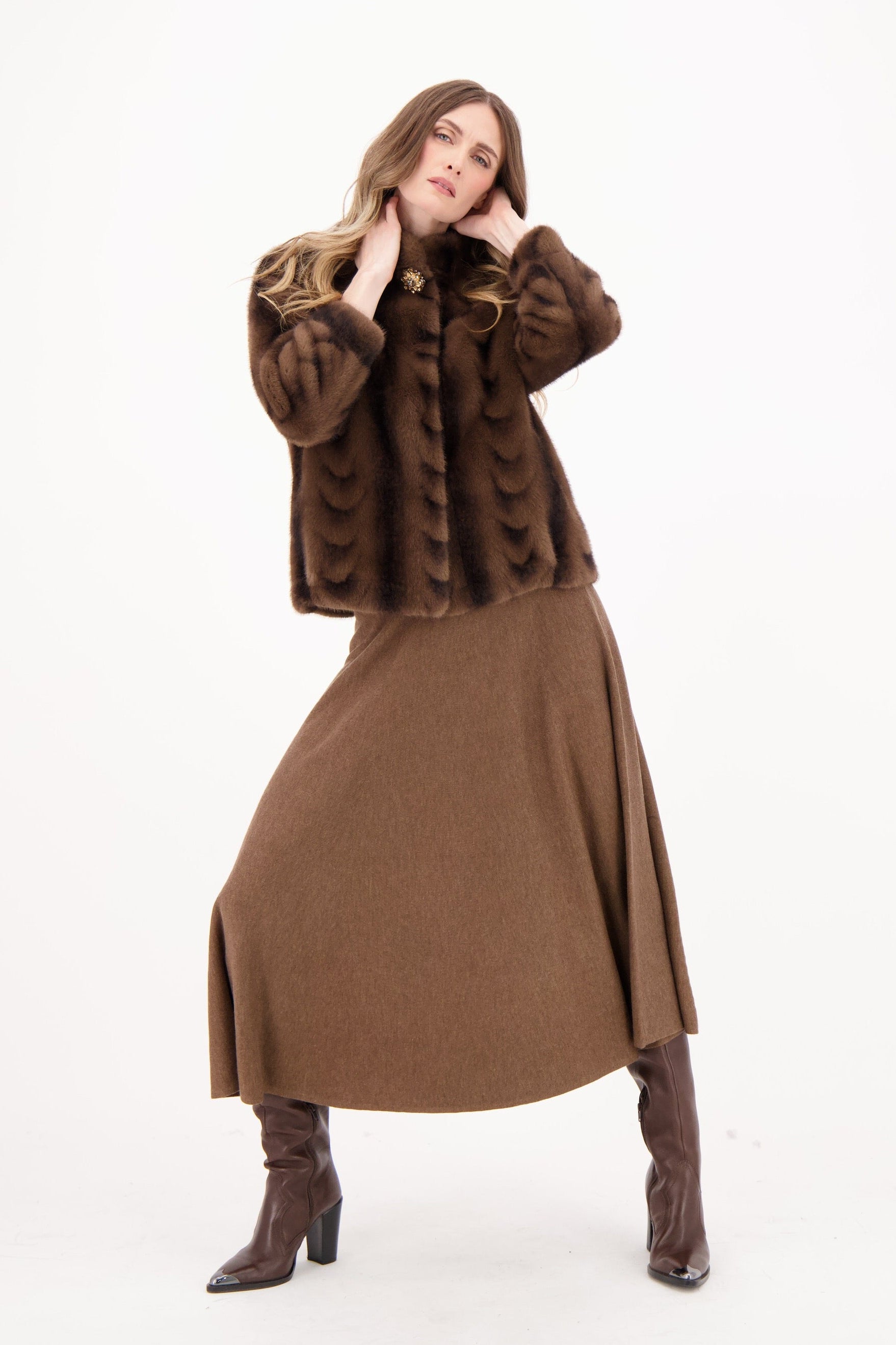 Woman wearing a brown fur coat, brown dress, and brown boots on a white background