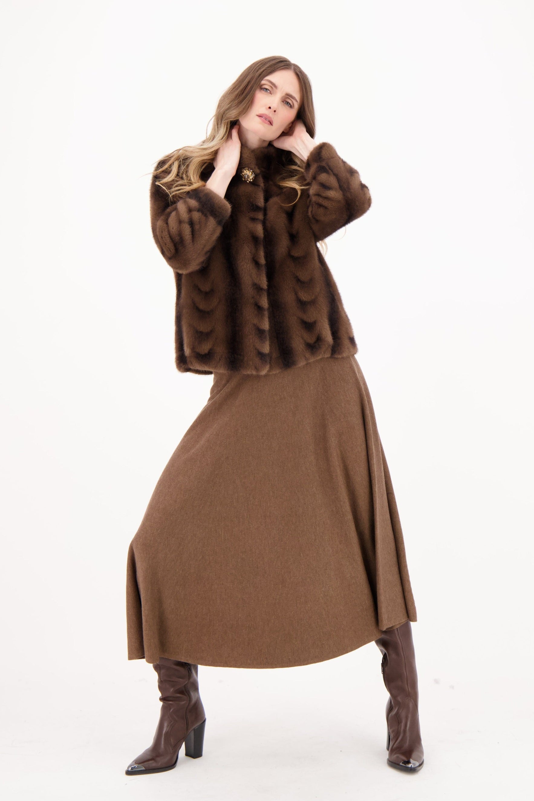 Woman wearing a brown fur coat, brown dress, and brown boots on a white background