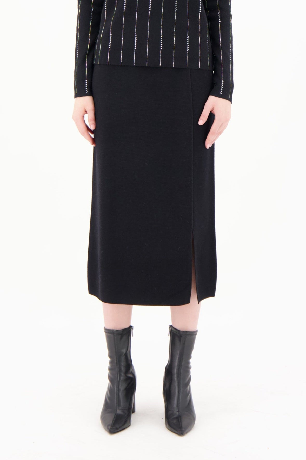 Woman wearing a black turtleneck with white stripes and a black skirt on a white background