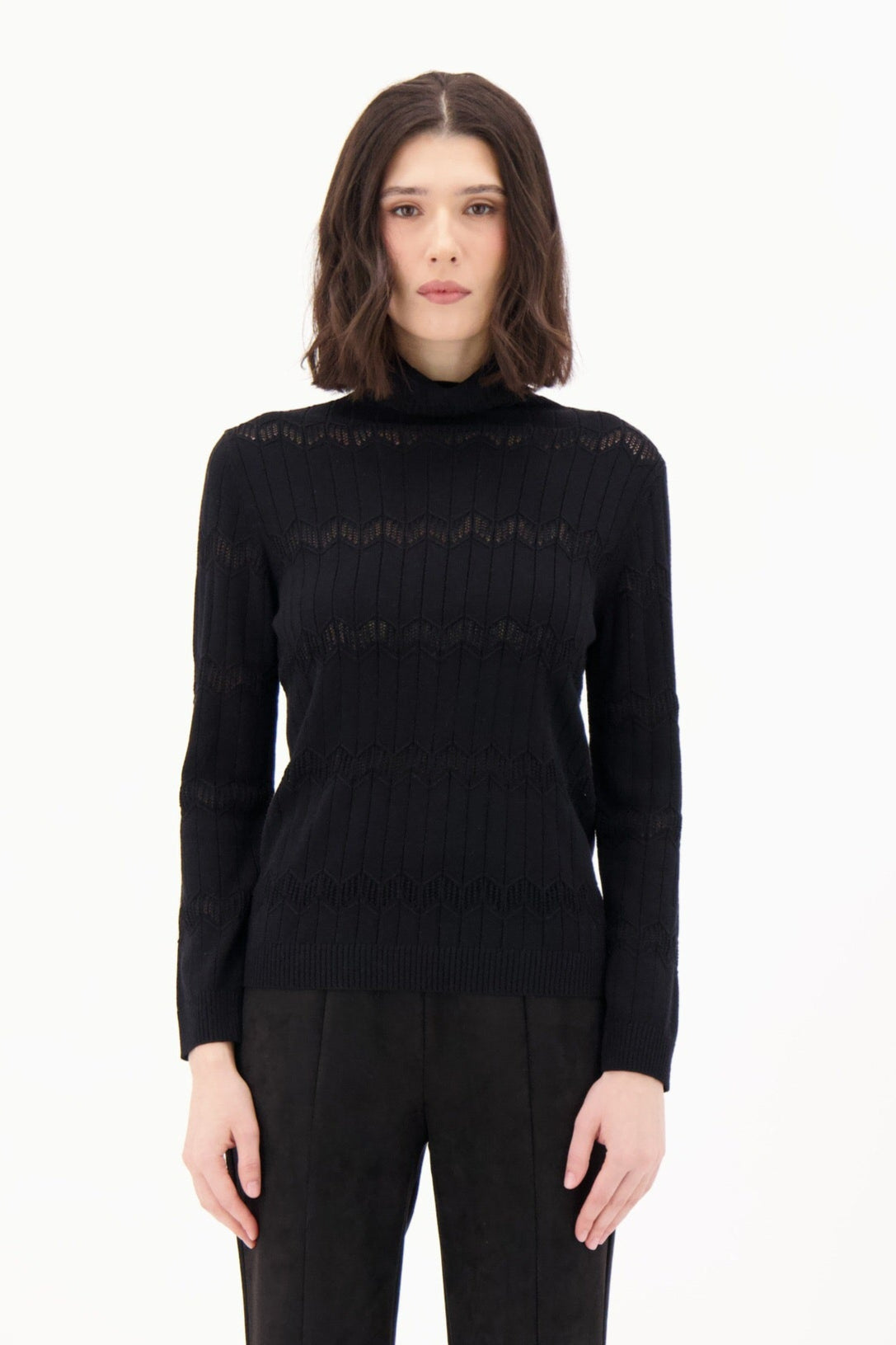 Person wearing a black turtleneck and black pants on a white background