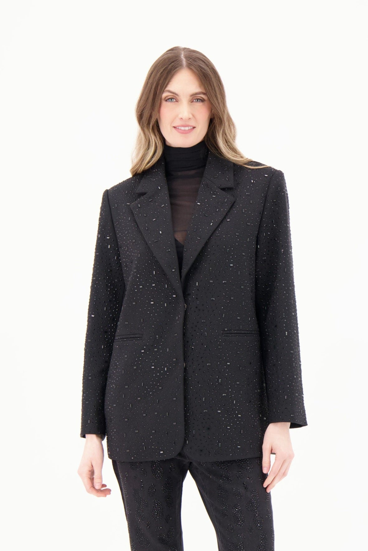 Woman wearing a black textured blazer and pants on a white background