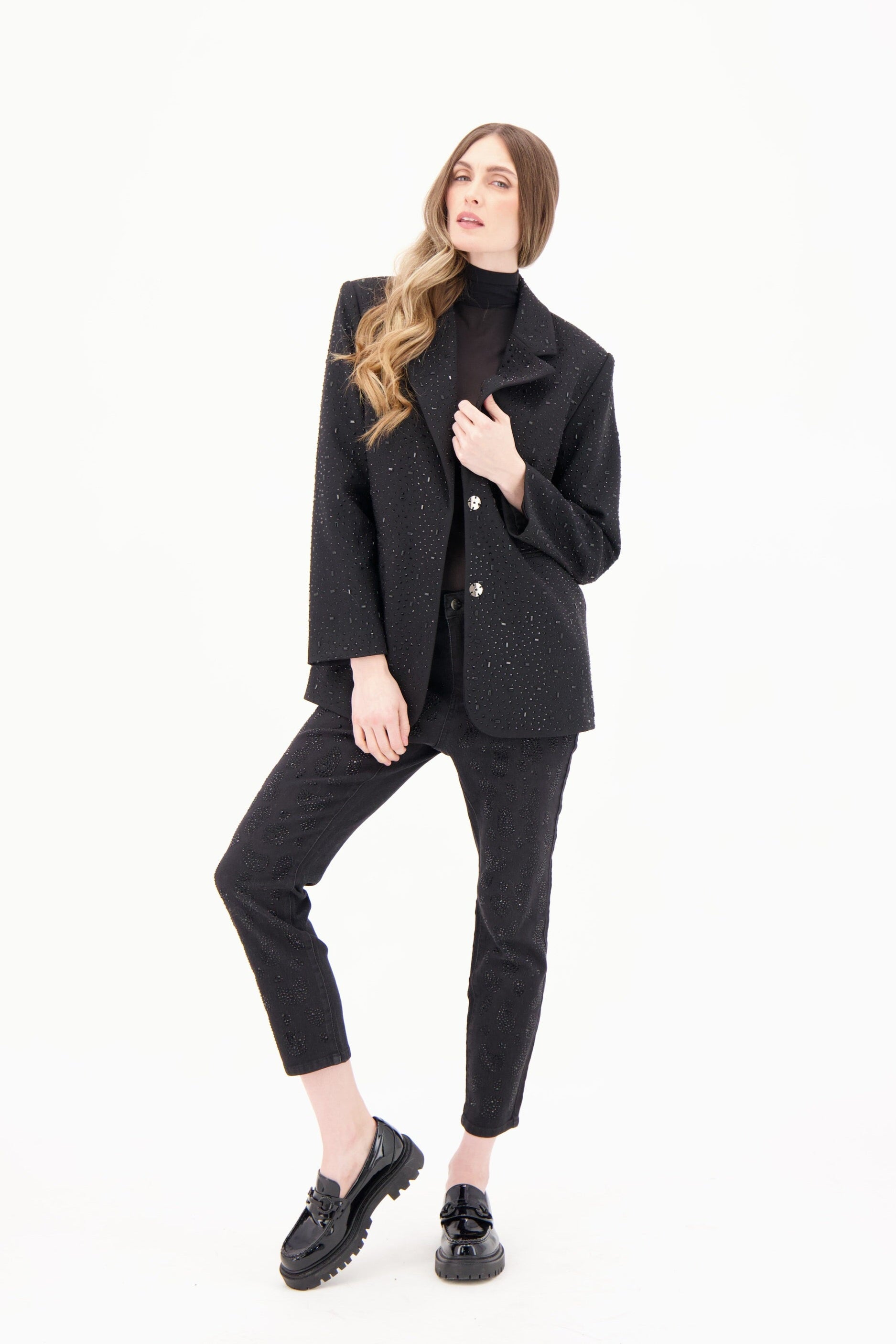 Woman wearing a black outfit with a blazer and pants on a white background