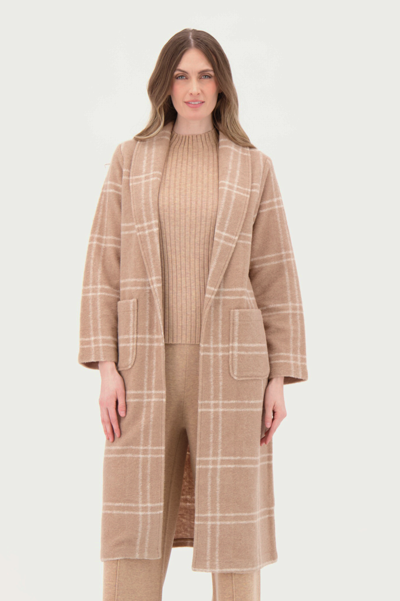 Woman wearing a beige checkered coat and pants on a white background