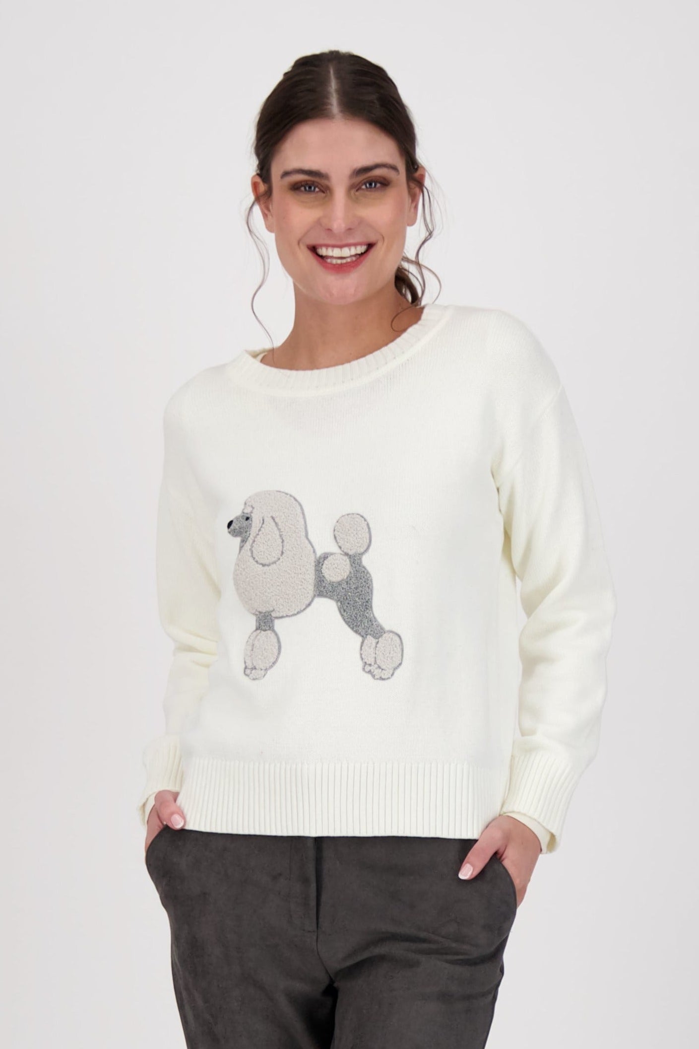 Woman wearing a cream sweater with a poodle design on a white background