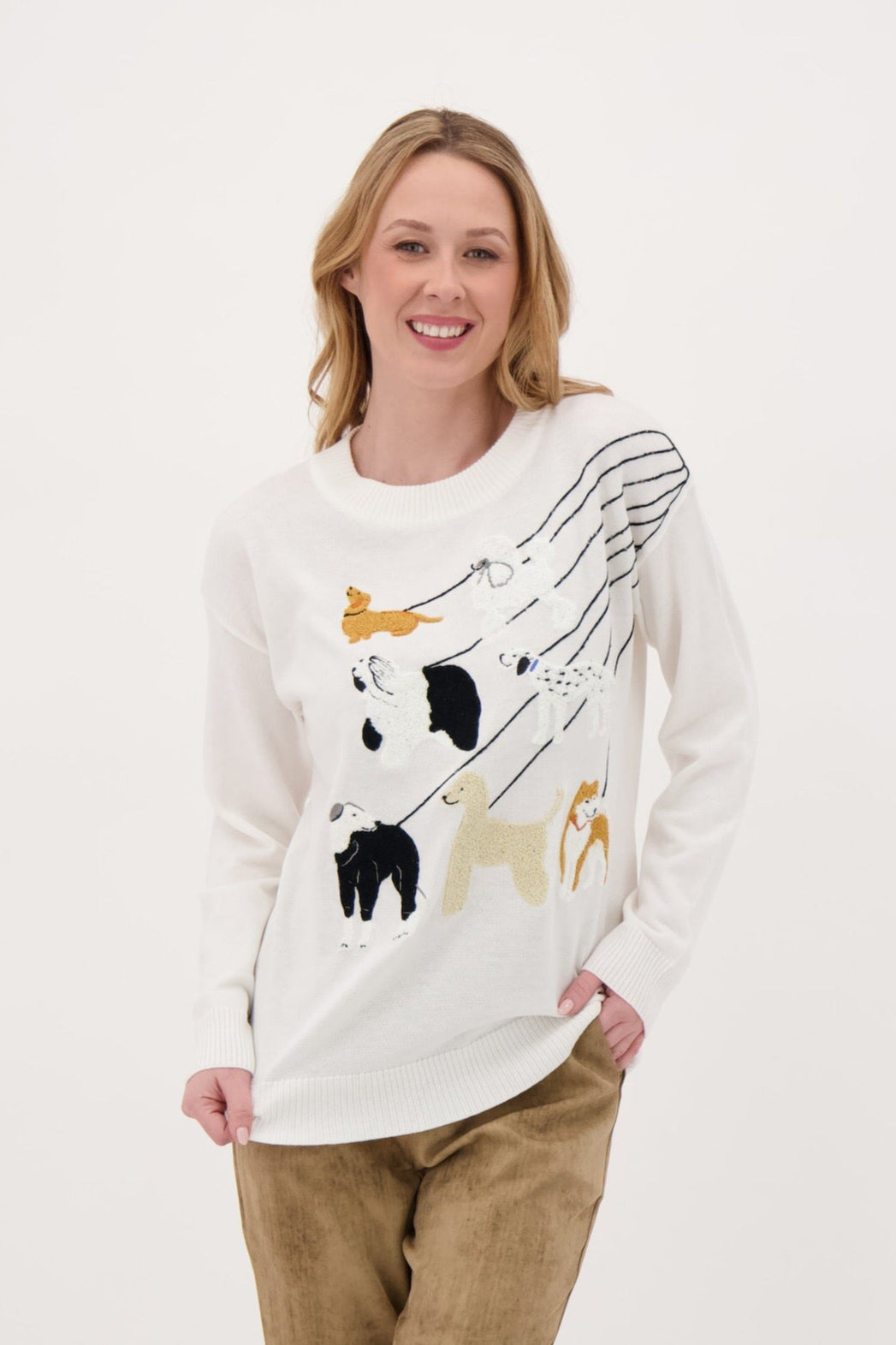 Woman wearing a white sweater with animal prints and brown pants on a white background