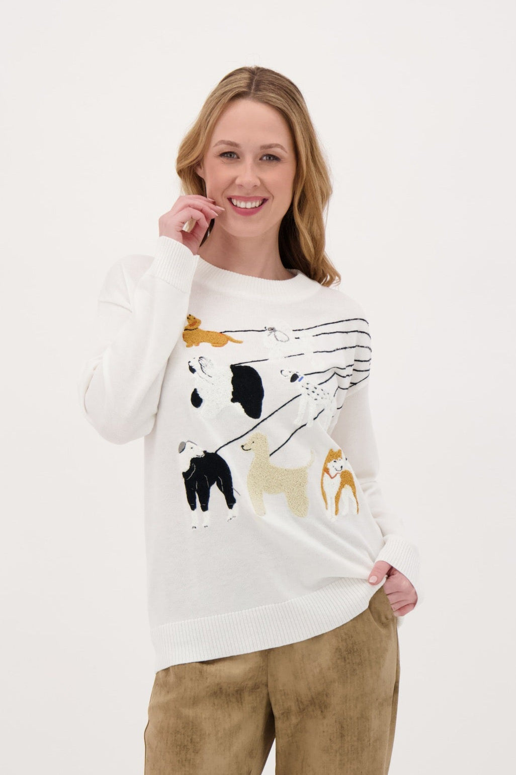 Woman wearing a white sweater with cat designs and beige pants on a white background