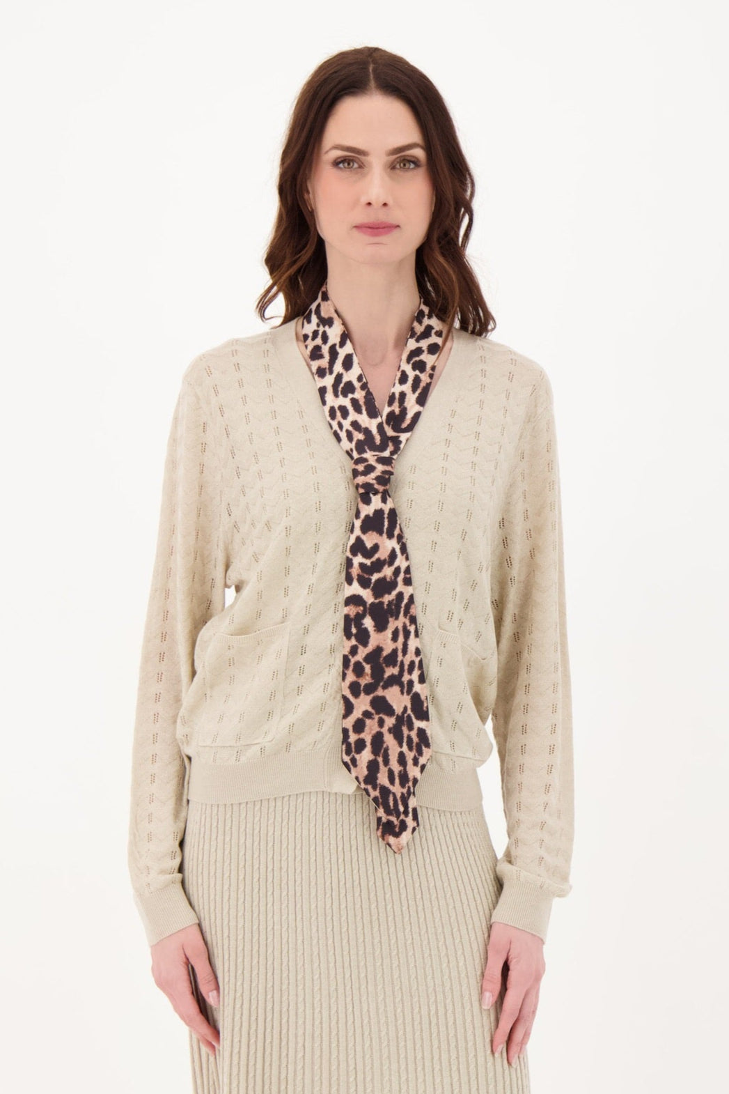 Woman wearing a beige ribbed dress with a patterned scarf on a white background