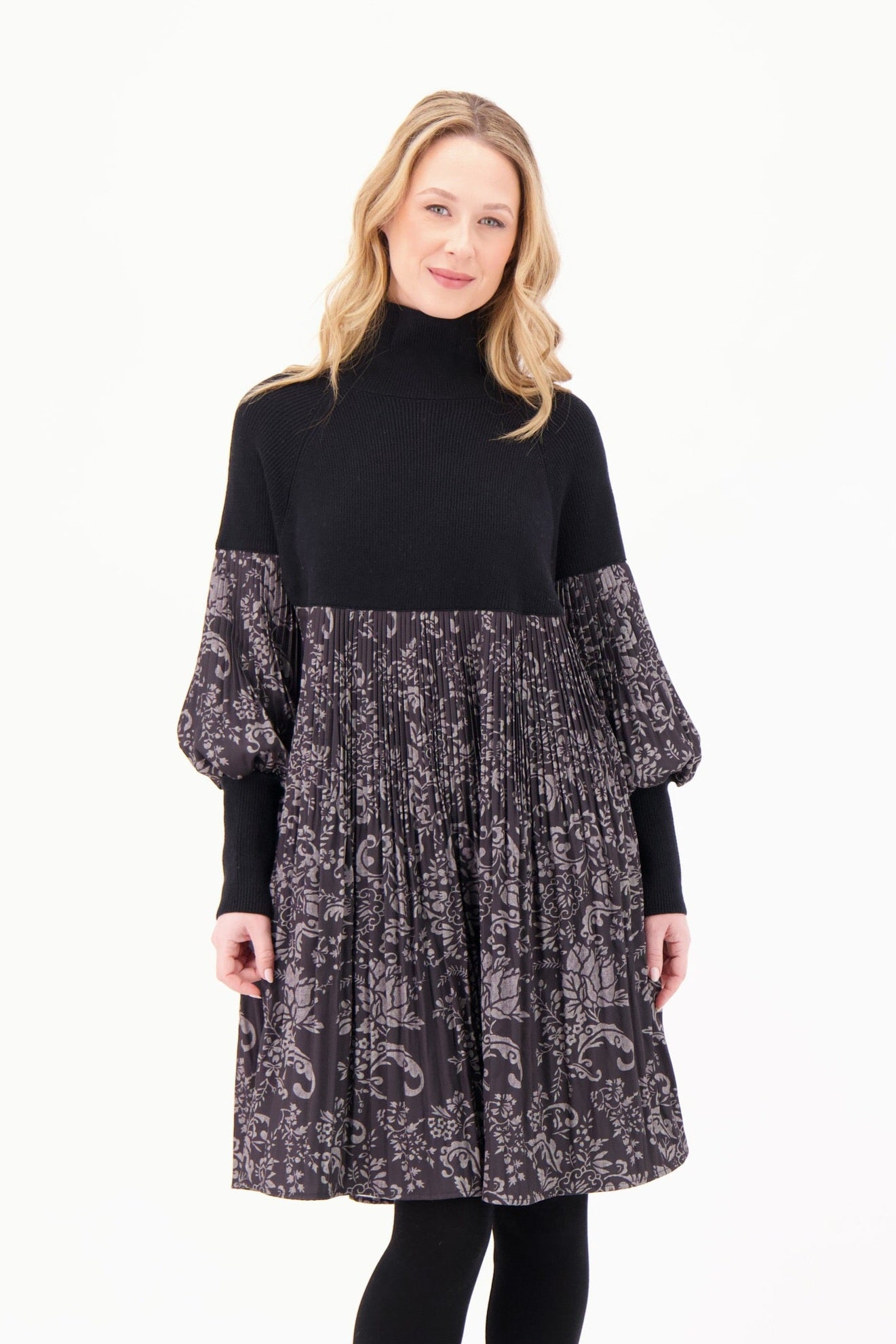 Woman wearing a black turtleneck dress with floral patterned sleeves on a white background
