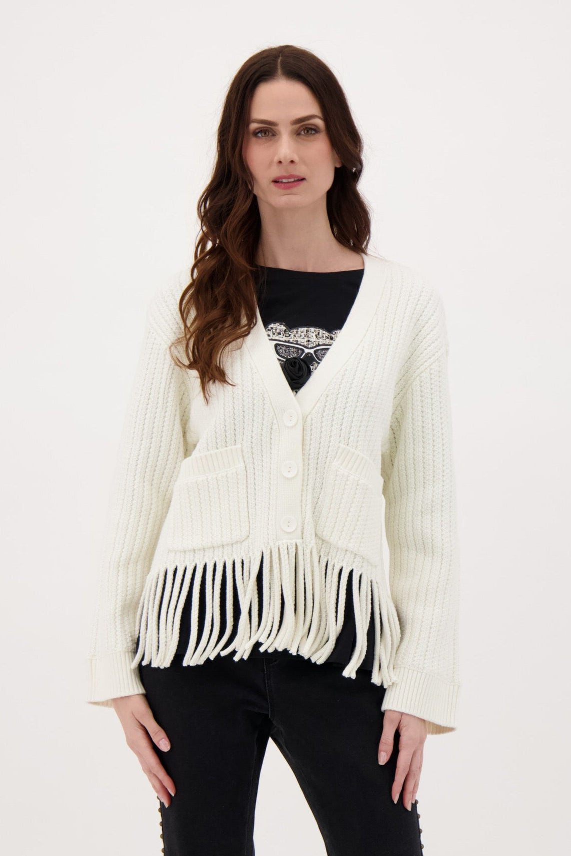 Woman wearing a white fringed cardigan over a black top and pants on a white background