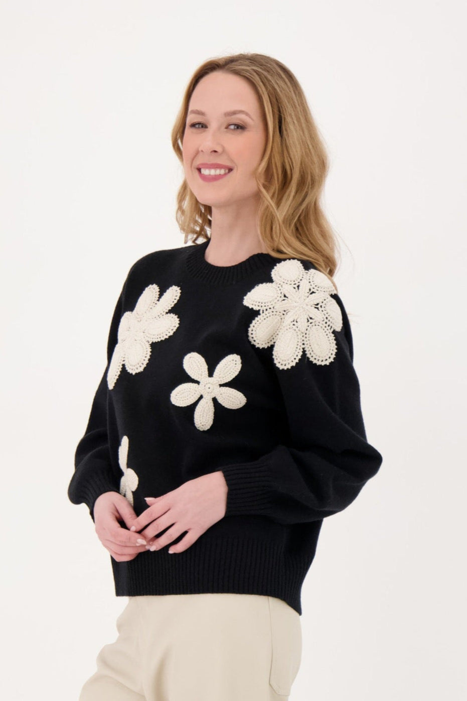 Woman wearing a black sweater with white floral patterns on a white background