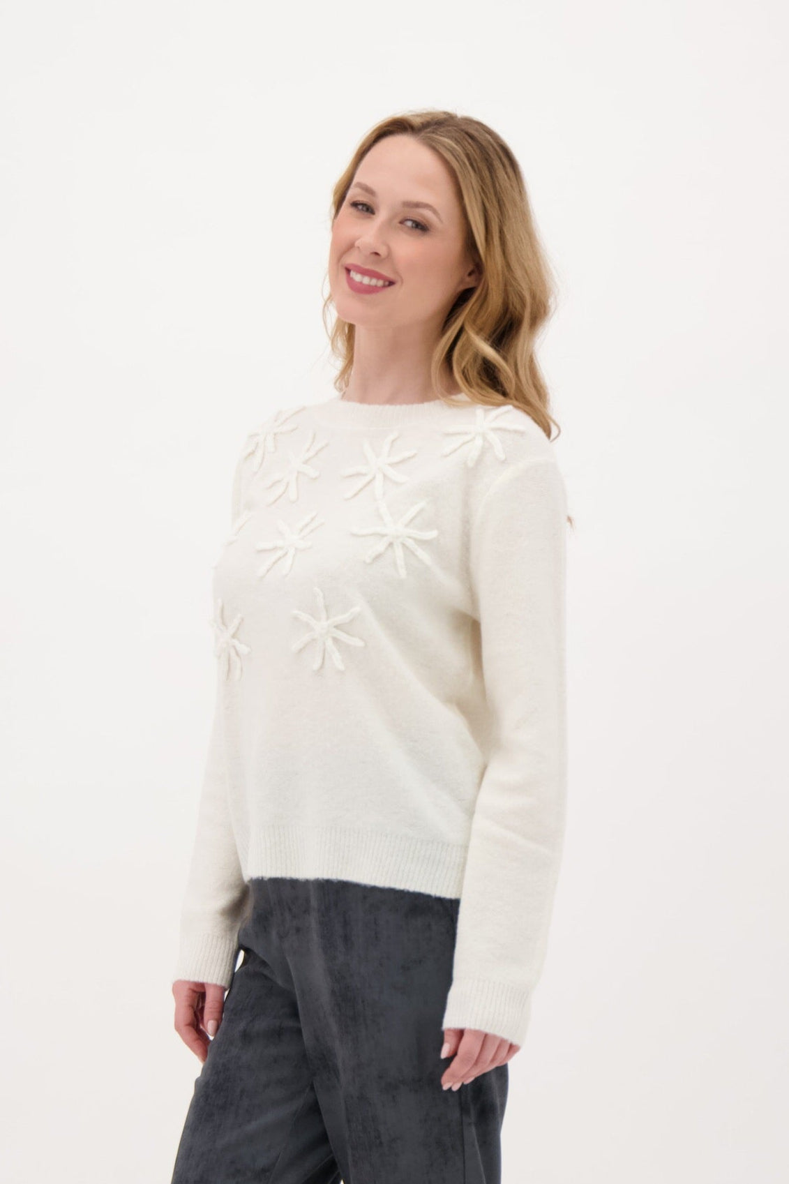 Woman wearing a white sweater with a star pattern on a white background