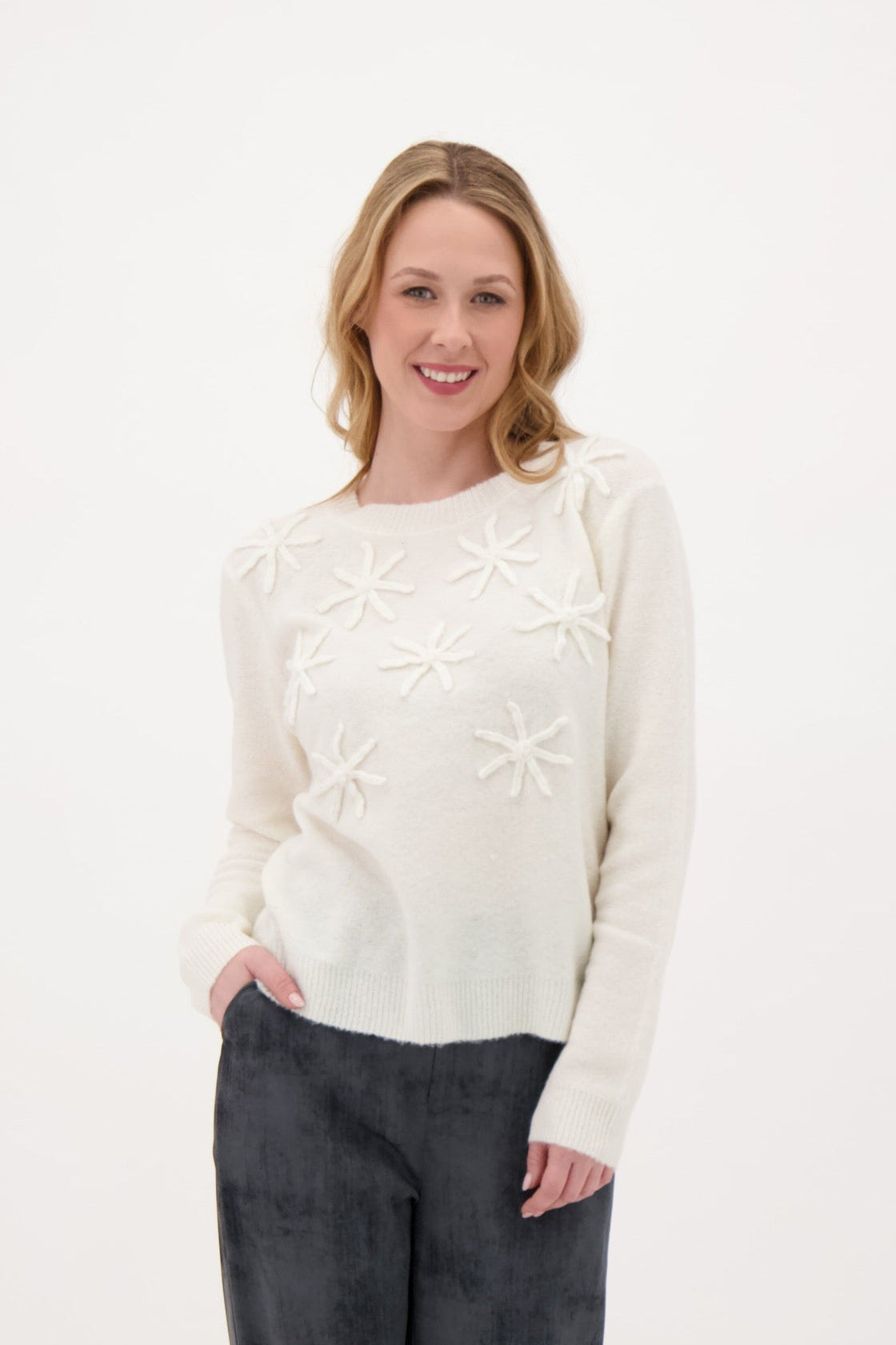 Woman wearing a cream sweater with a star pattern on a white background