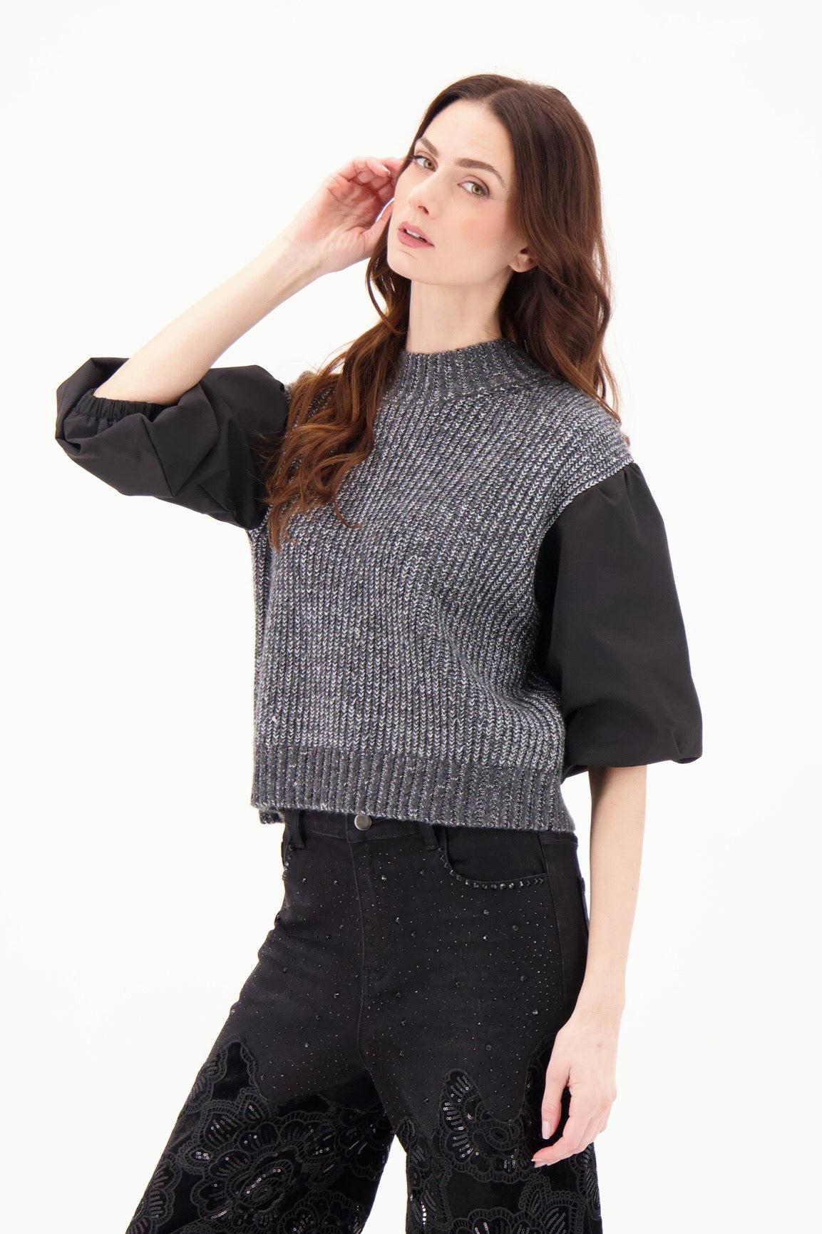 Woman wearing a black and gray sweater with wide-leg pants on a white background