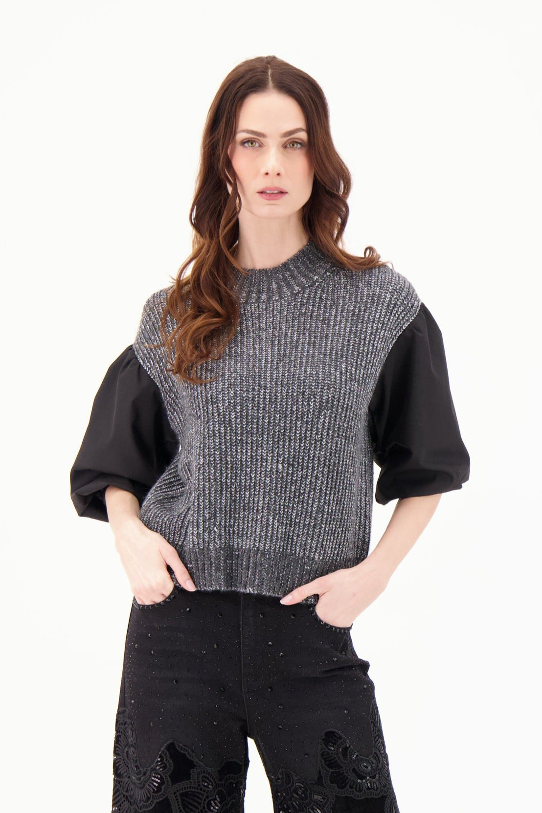 Woman wearing a black and gray sweater with black pants on a white background