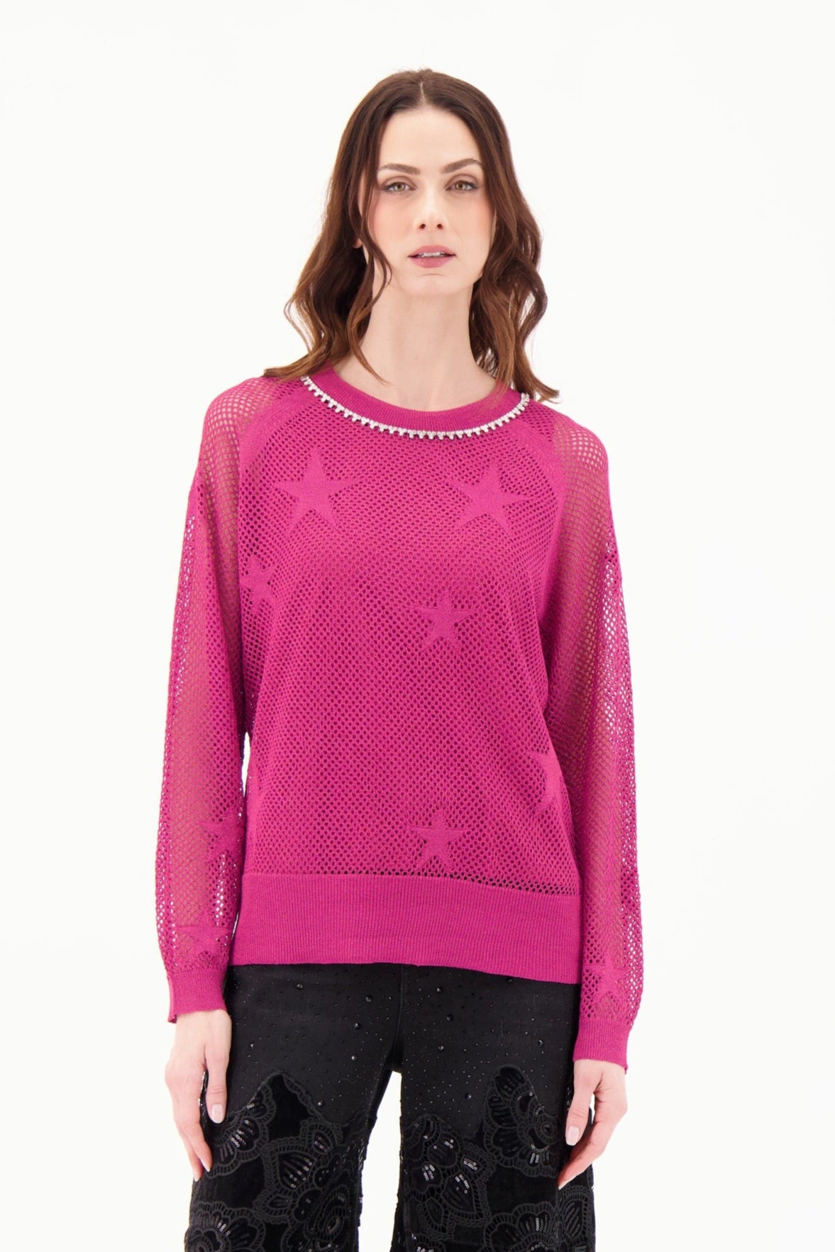 Woman wearing a pink sweater and black lace pants on a white background