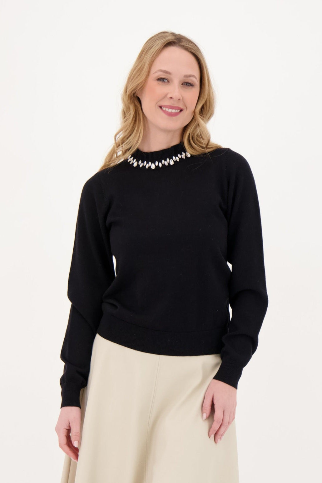Woman wearing a black sweater and beige skirt on a white background 