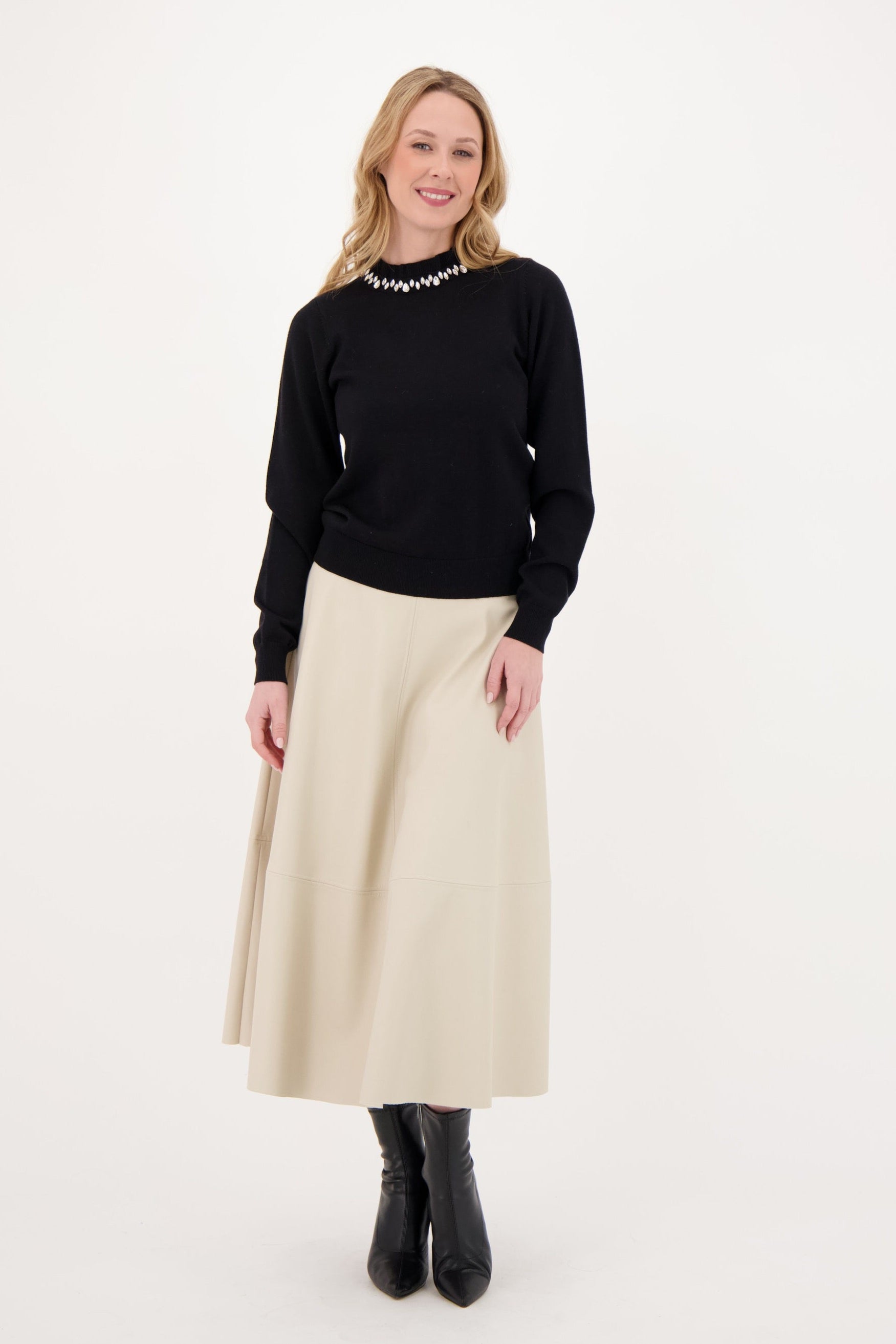 Woman wearing a black sweater and beige skirt on a white background
