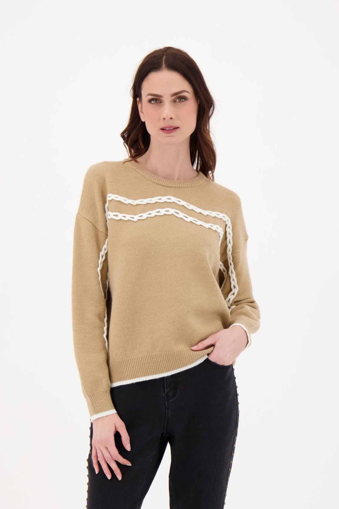 Woman wearing a beige sweater with white chain detail on a white background