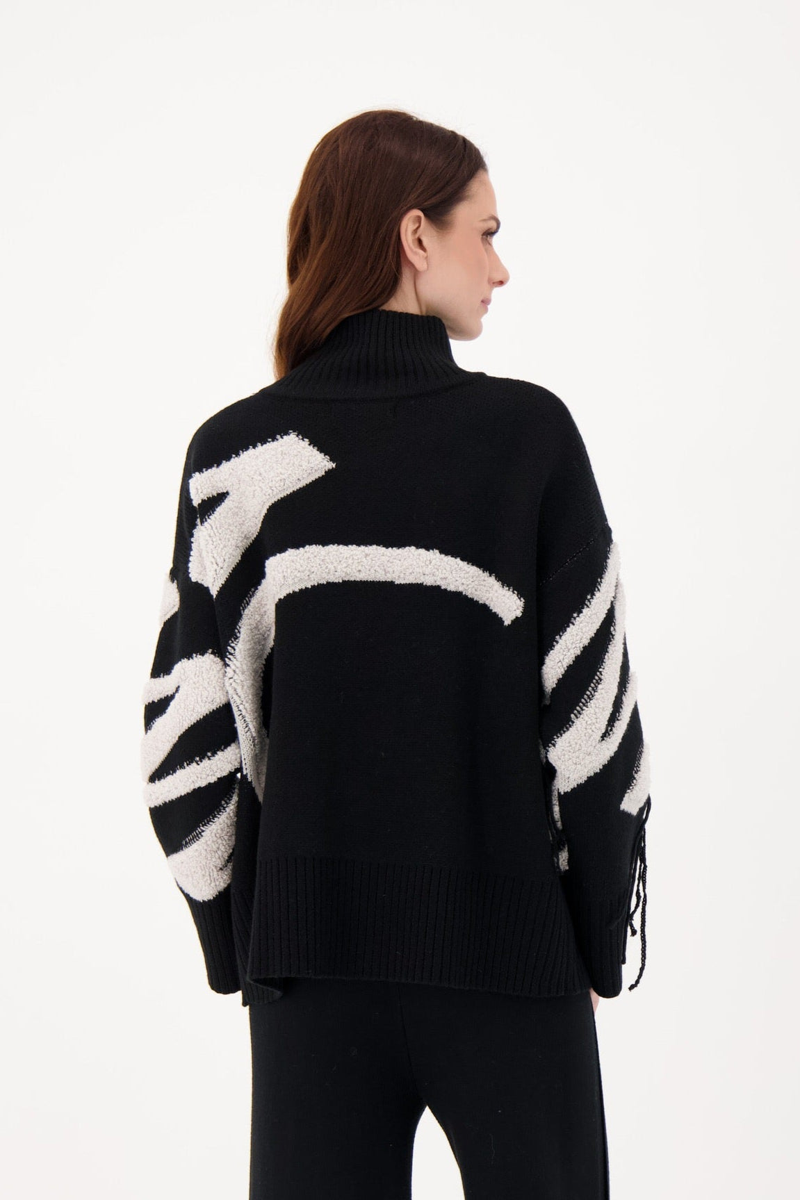 Person wearing a black sweater with white abstract patterns on a white background