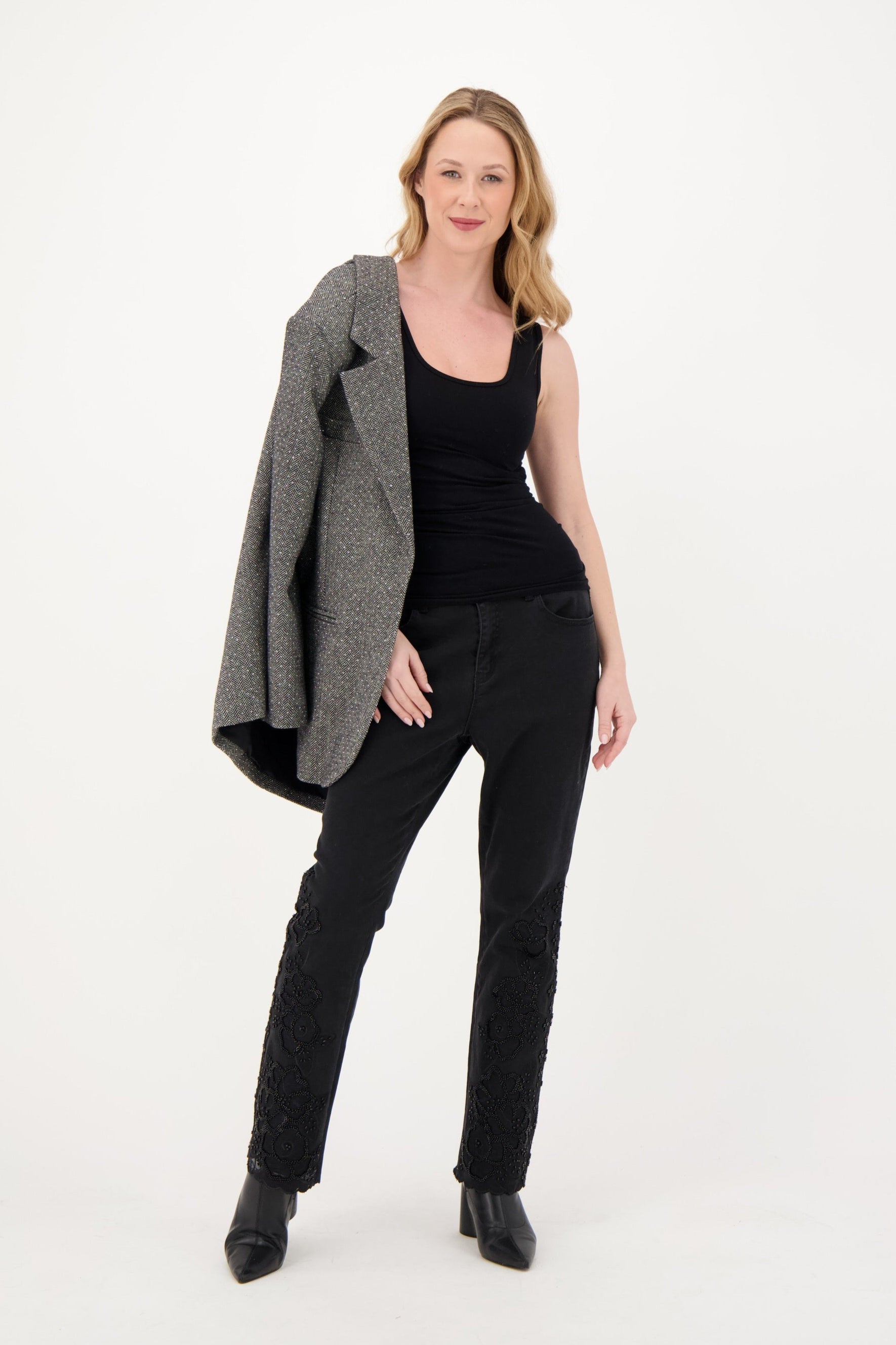 Woman wearing a gray blazer, black top, and black pants on a white background