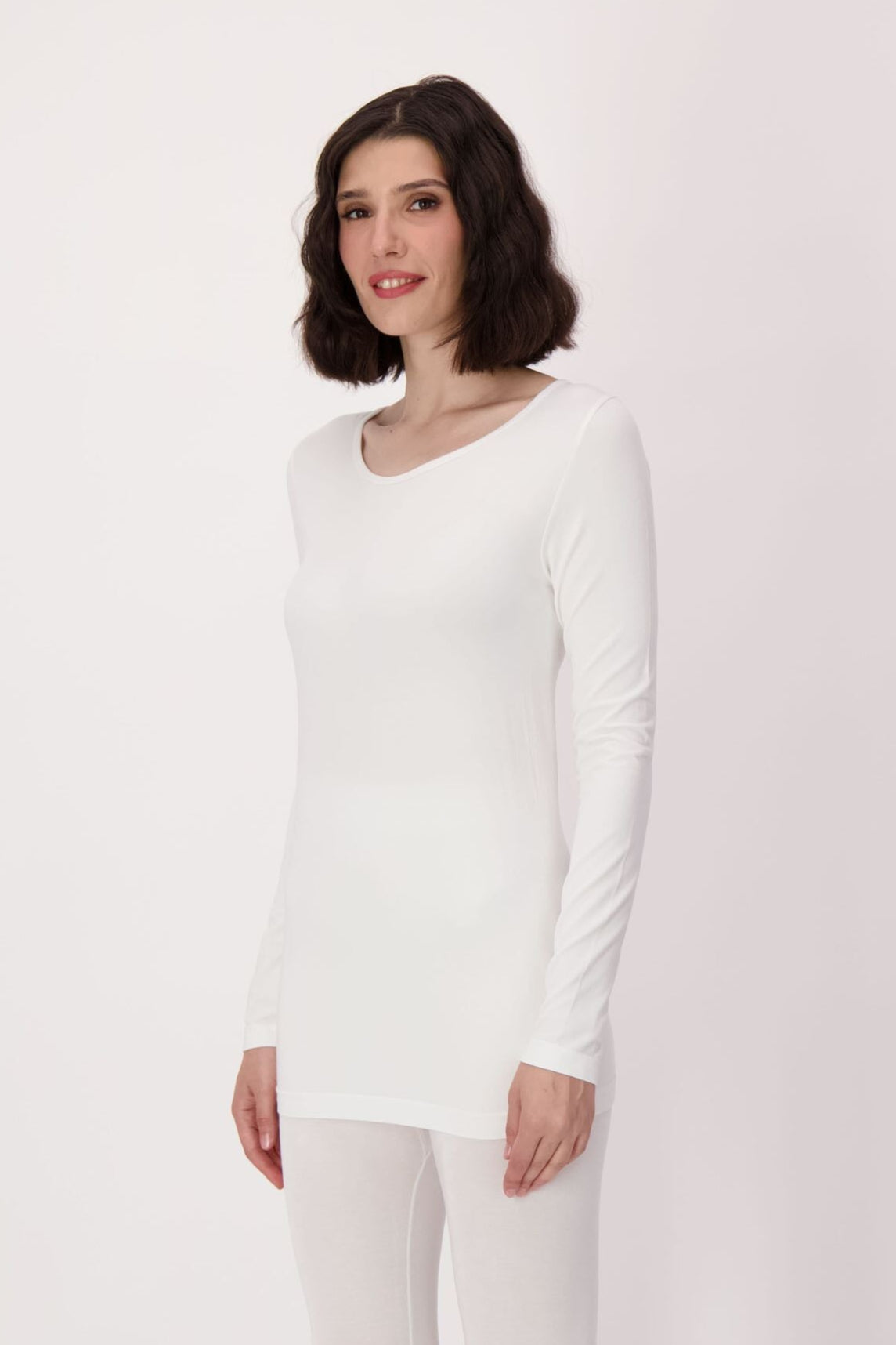 Woman wearing a white long-sleeve top and pants on a white background 