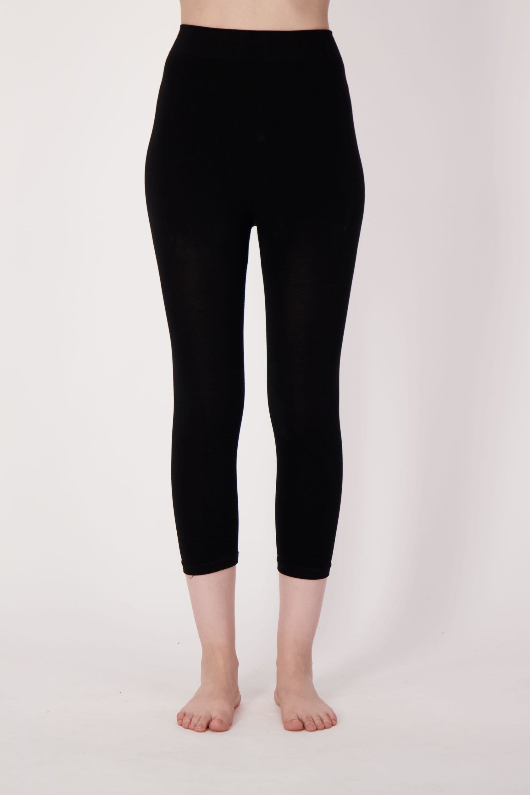 Person wearing black leggings on a plain background